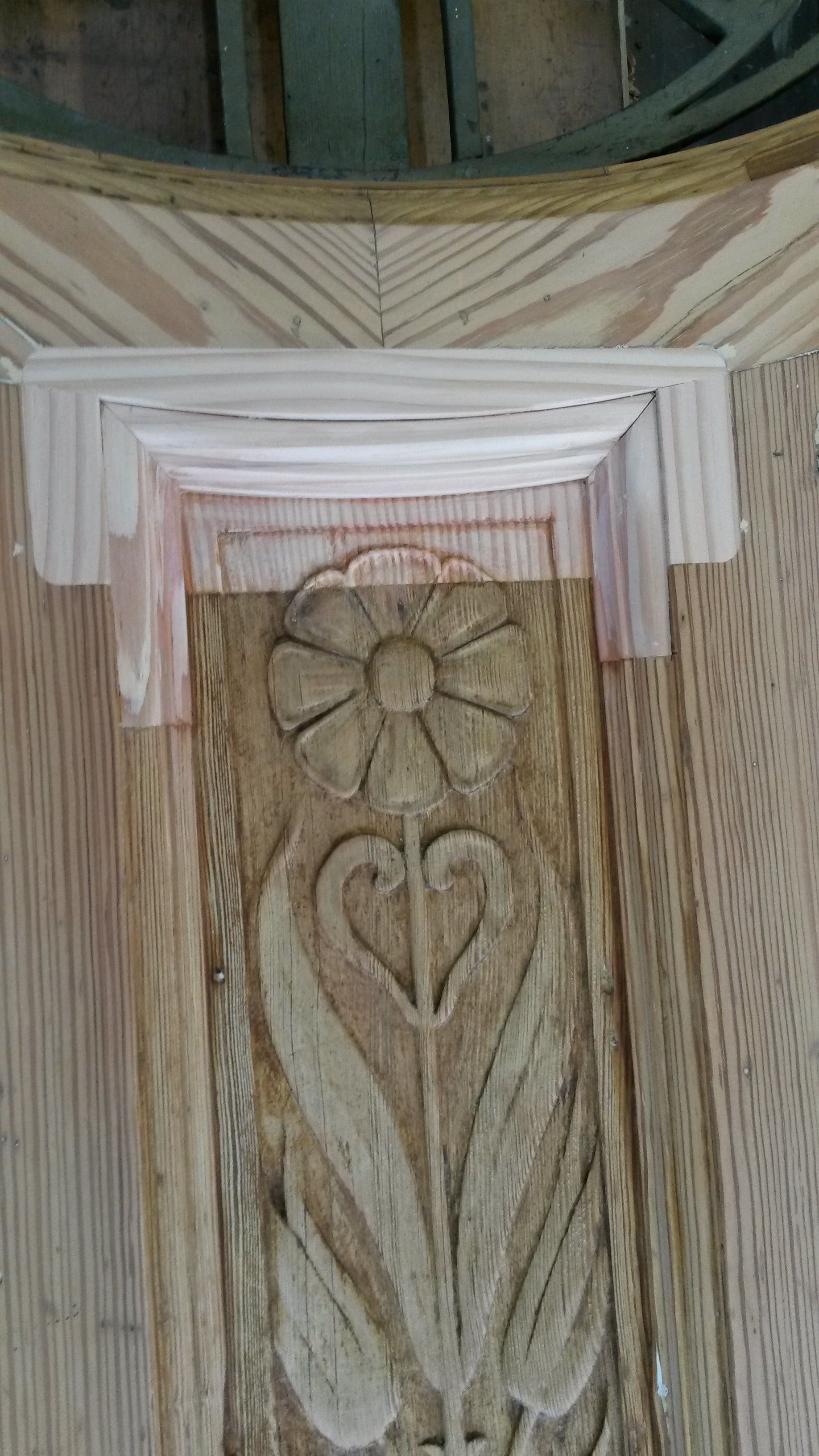 Eine Nahaufnahme einer Holzschnitzerei einer Blume und Blätter auf einer Holzoberfläche.