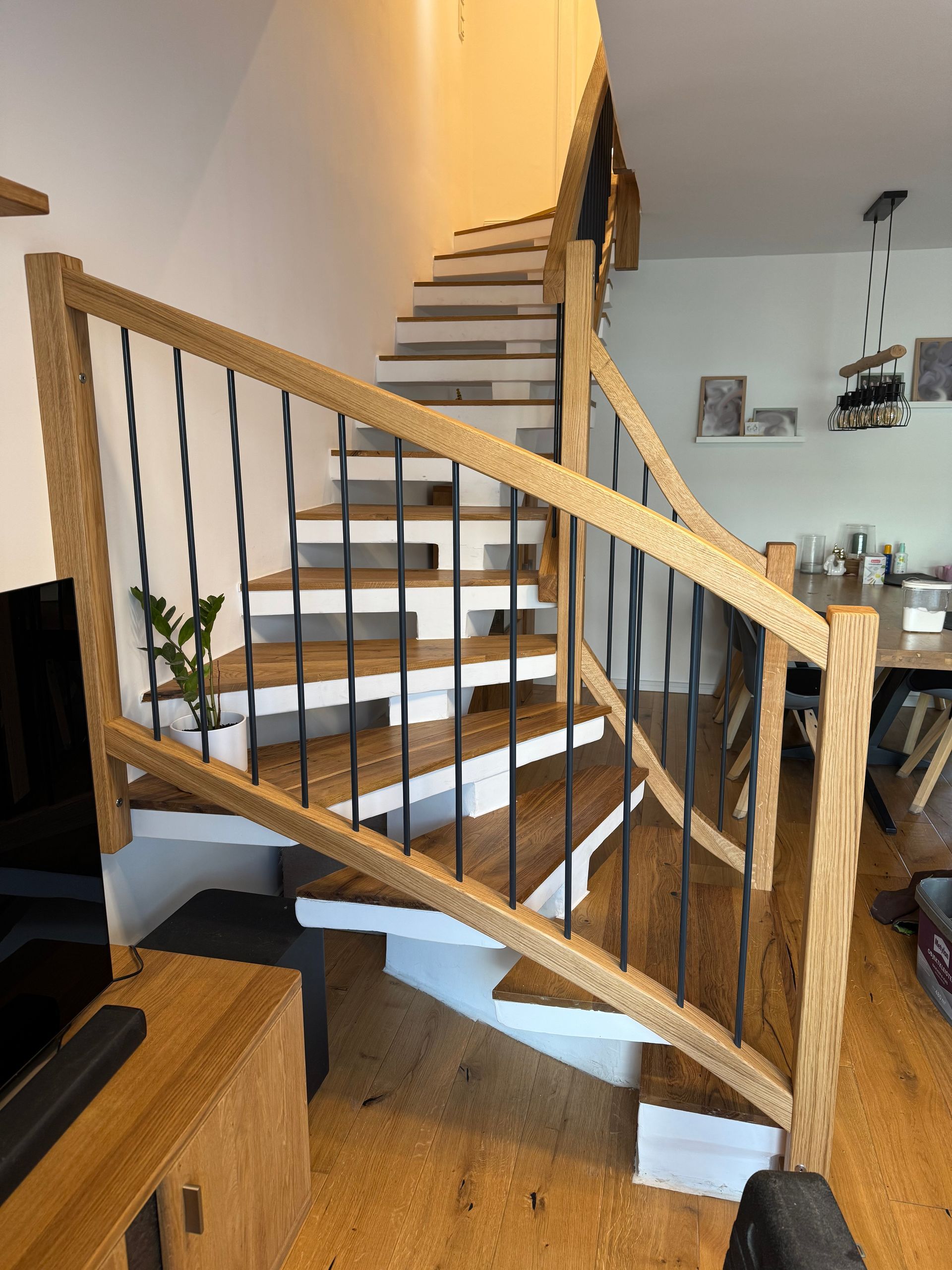 Holztreppe mit geschwungenem Geländer in einem modernen Wohninterieur, die in ein Obergeschoss führt