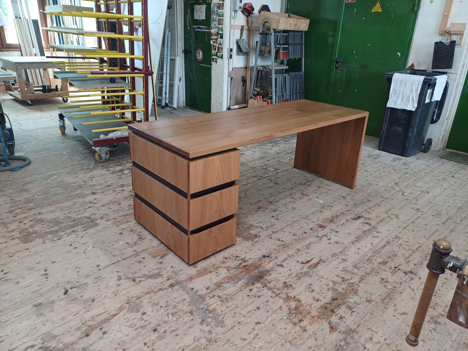 Ein Holzschreibtisch steht auf einem Holzboden in einer Werkstatt.