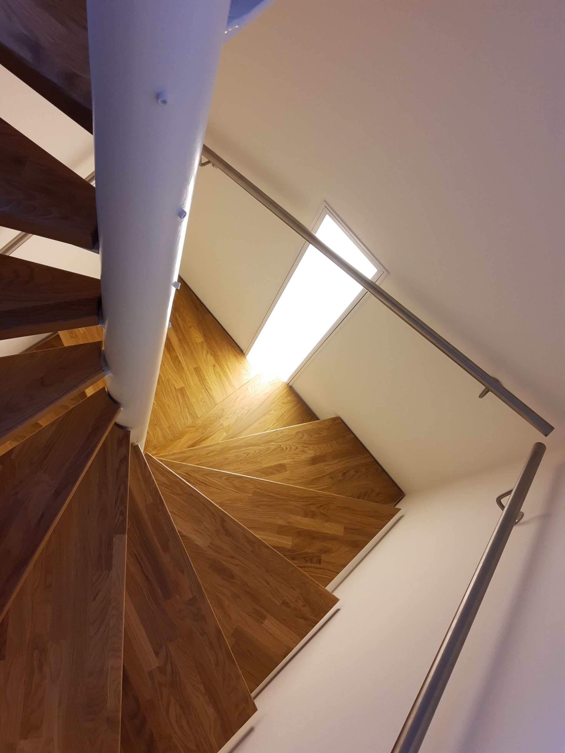 Eine Wendeltreppe mit Holzstufen und weißem Geländer