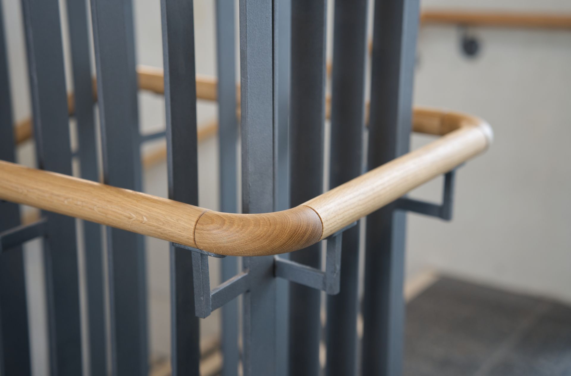 Holzhandlauf mit Metallstützen in einem Treppenhaus, Nahaufnahme.