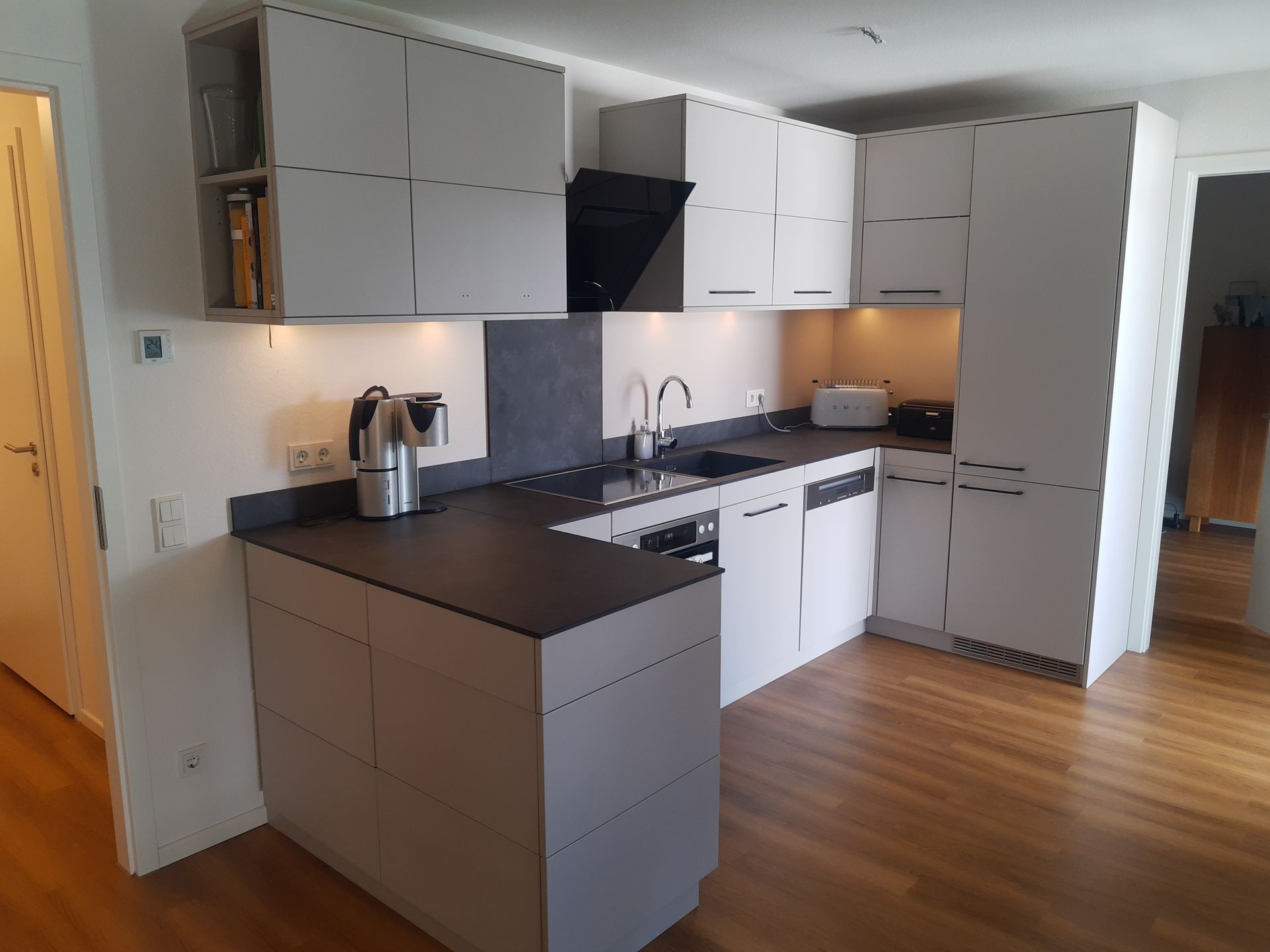 Eine Küche mit weißen Schränken und einer schwarzen Arbeitsplatte