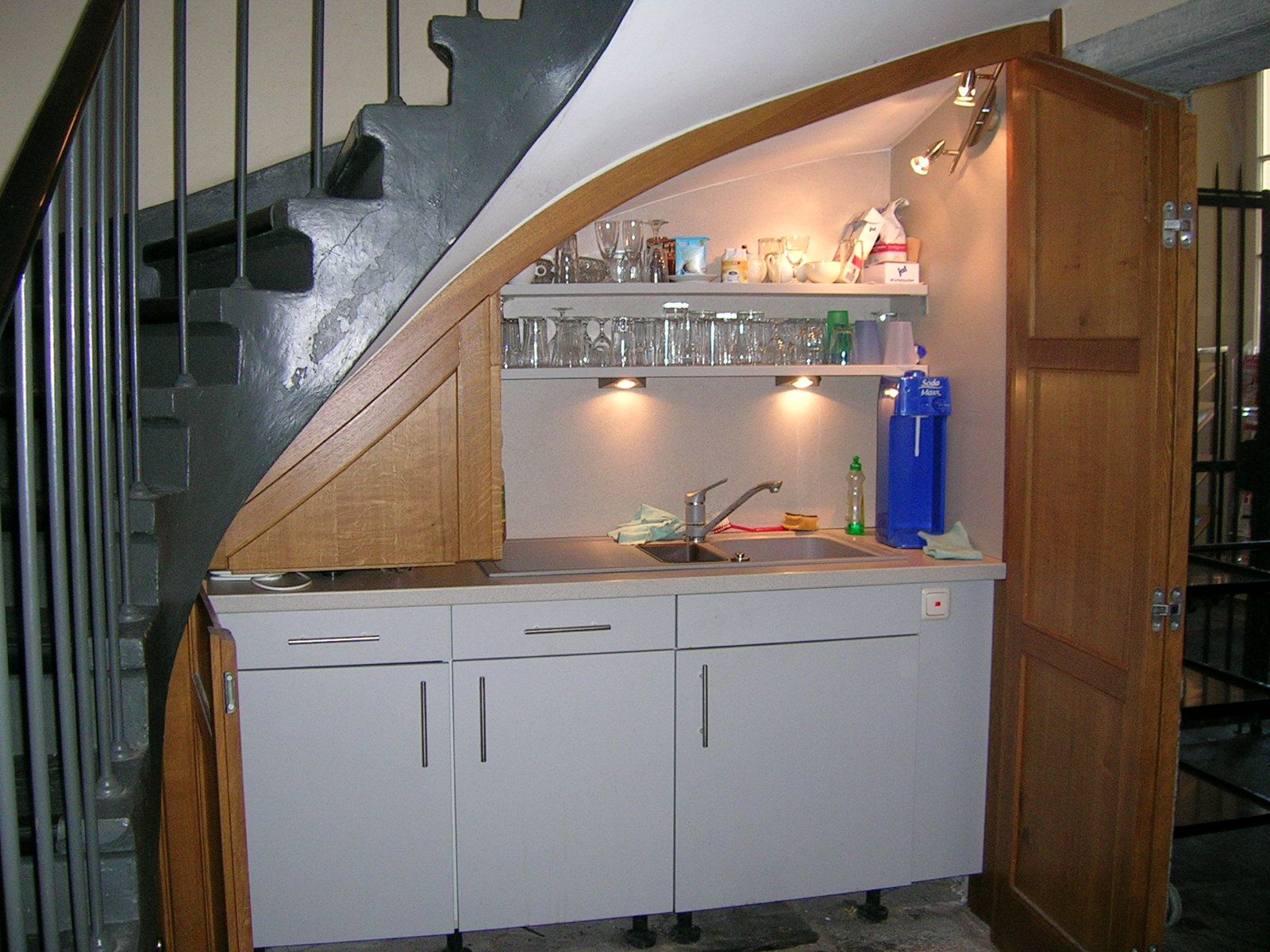 Eine Küche mit Spüle und Regalen unter einer Treppe