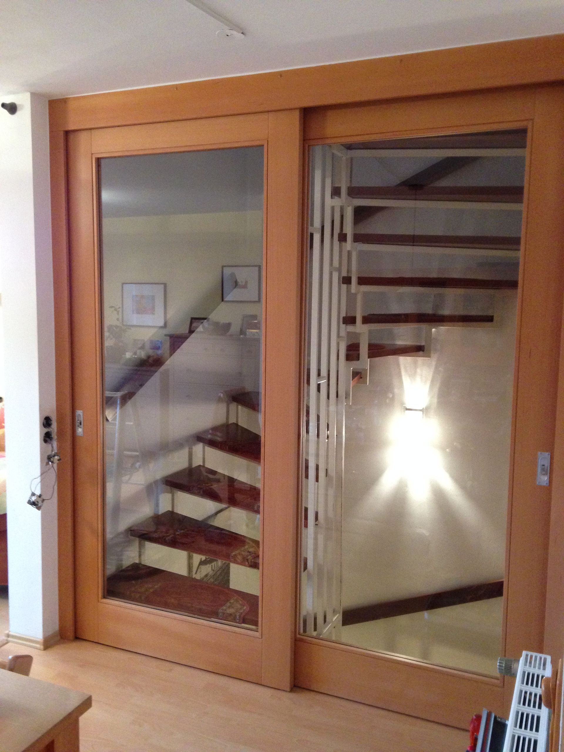 Durch eine Glasschiebetür ist eine Treppe sichtbar