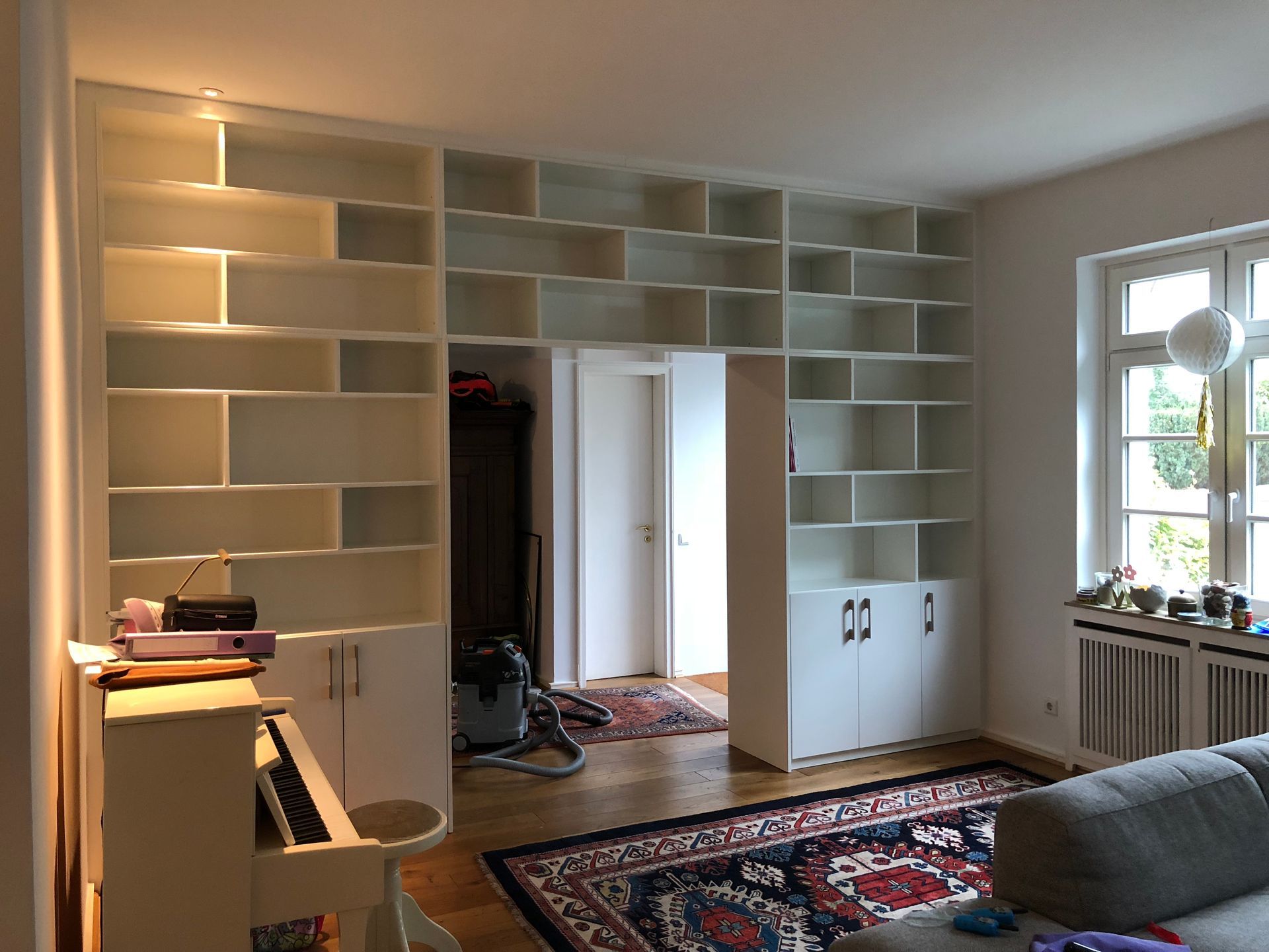 Ein Wohnzimmer mit Couch, Klavier und Regalen.