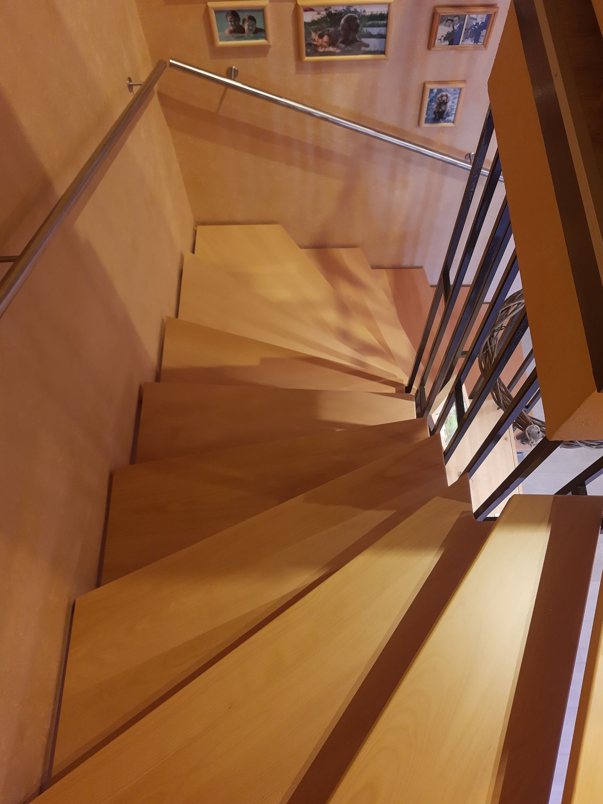 Eine hölzerne Wendeltreppe mit Bildern an der Wand dahinter