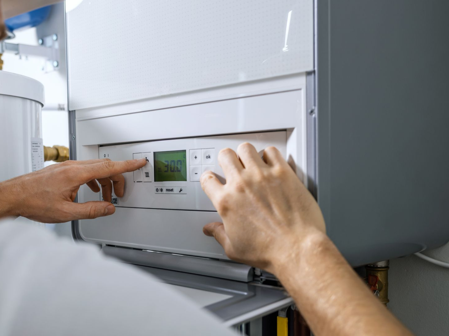 Personne ajustant les paramètres d'un système de chauffage blanc ; vue rapprochée.