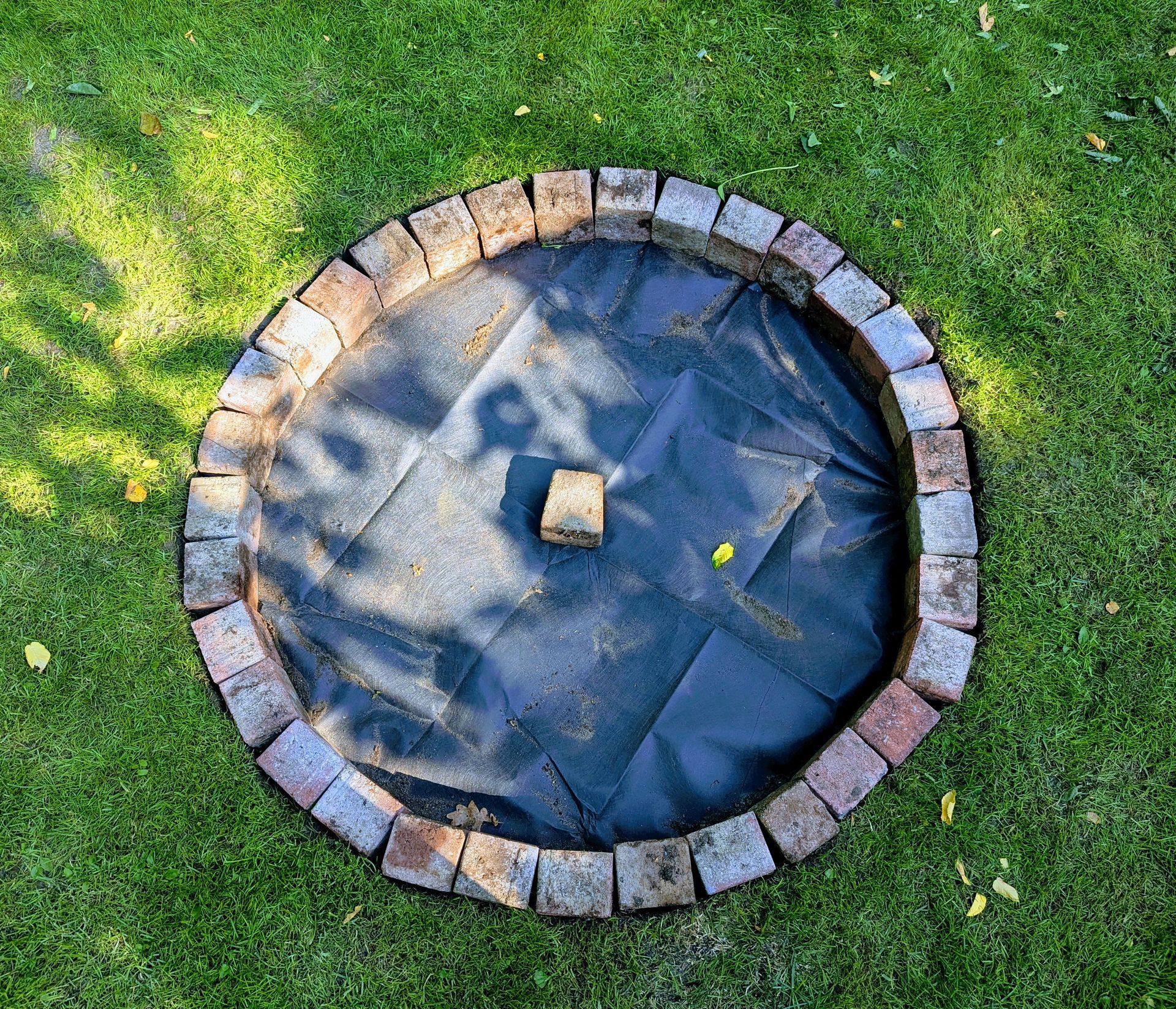 Rundesloch mir Pflastersteinen am Rand und Gartenvlies in der Mitte.