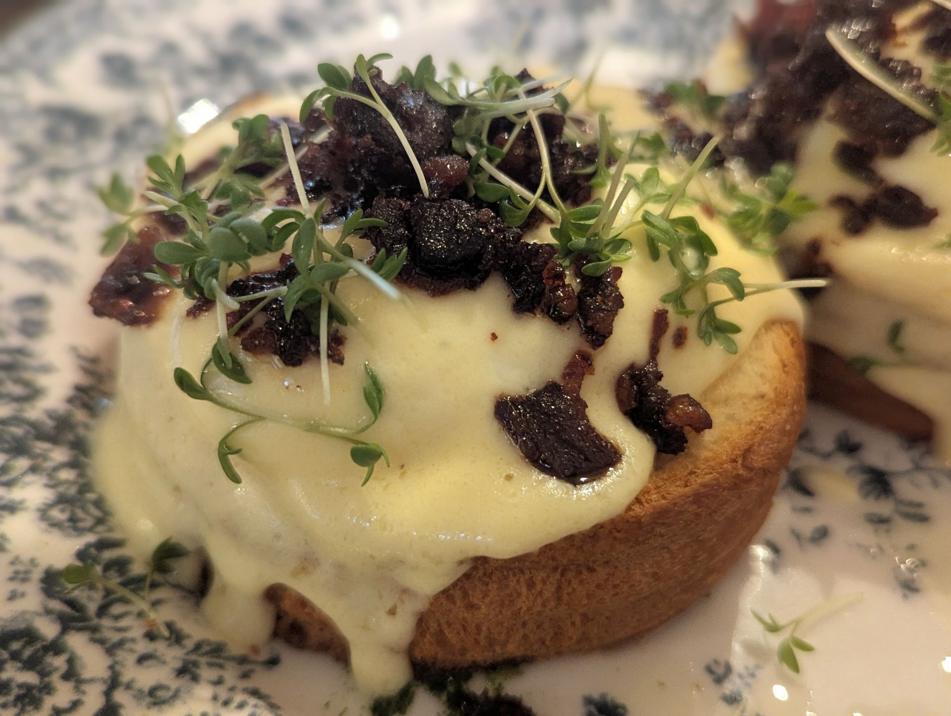 Knuspriger Toas, Egg Bendedict, krosser Speck auf einem Teller mit Blumenmuster.