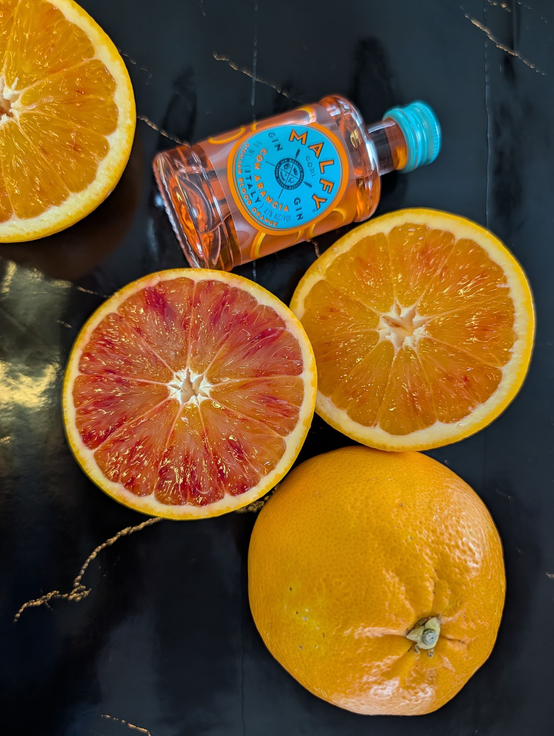 Blutorangen und Blutorangen-Gin auf dunklem Hintergrund