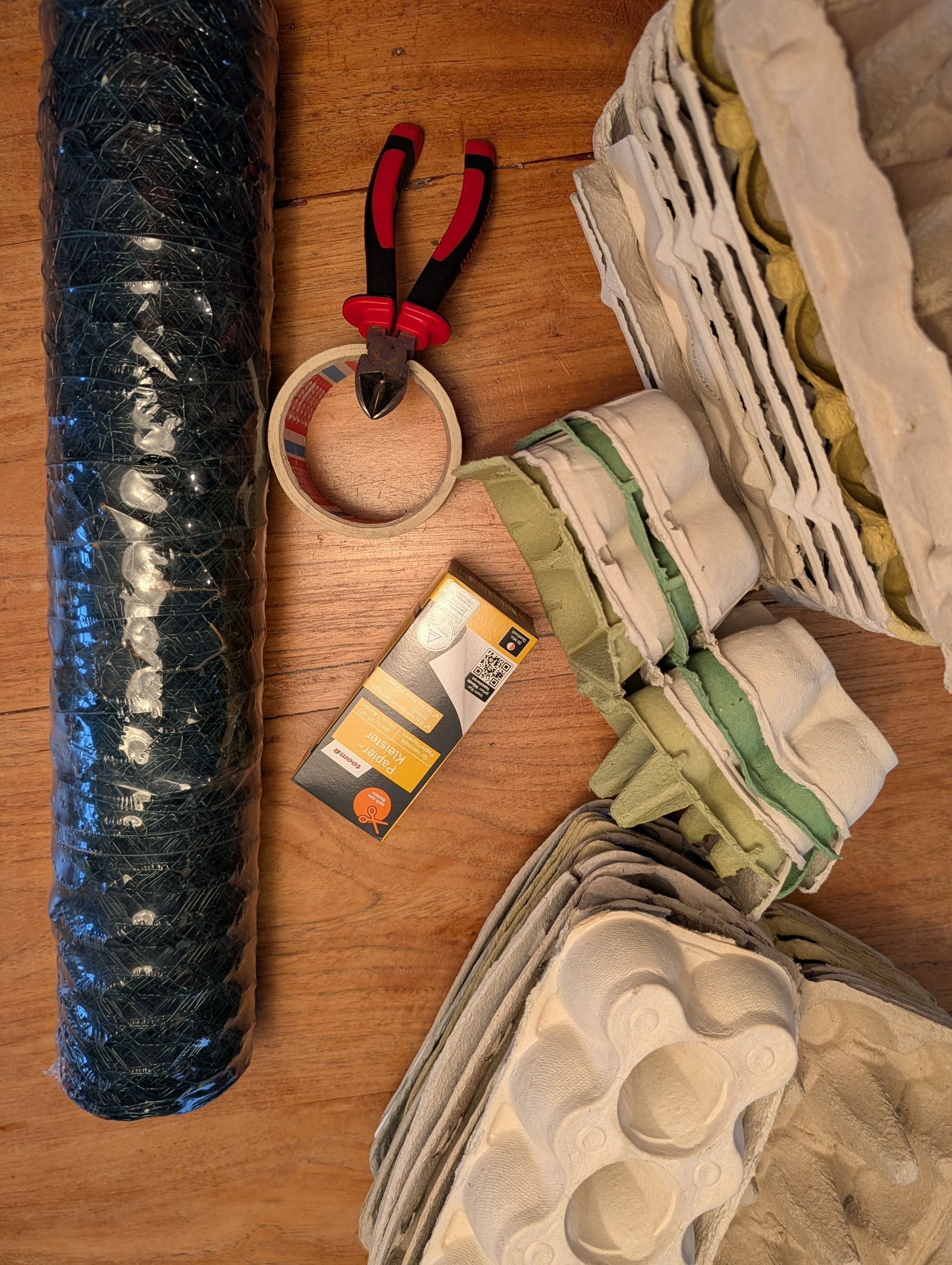Bastelmaterial wie Draht, Zange, Eierkarton und Kleister zum basteln einer Vase.