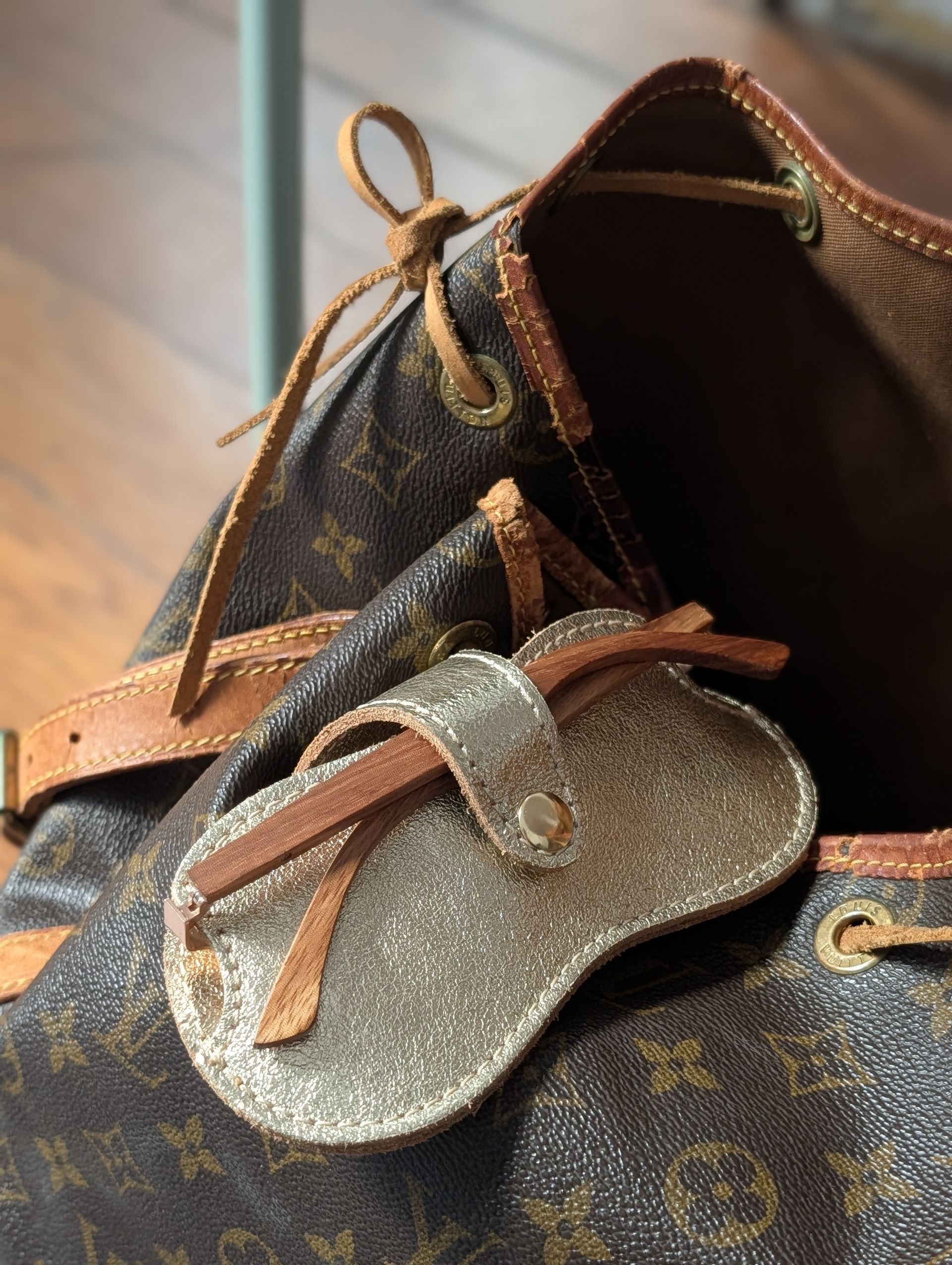 Sonnenbrillenhalter in gold an einer Louis Vuitton Tasche.