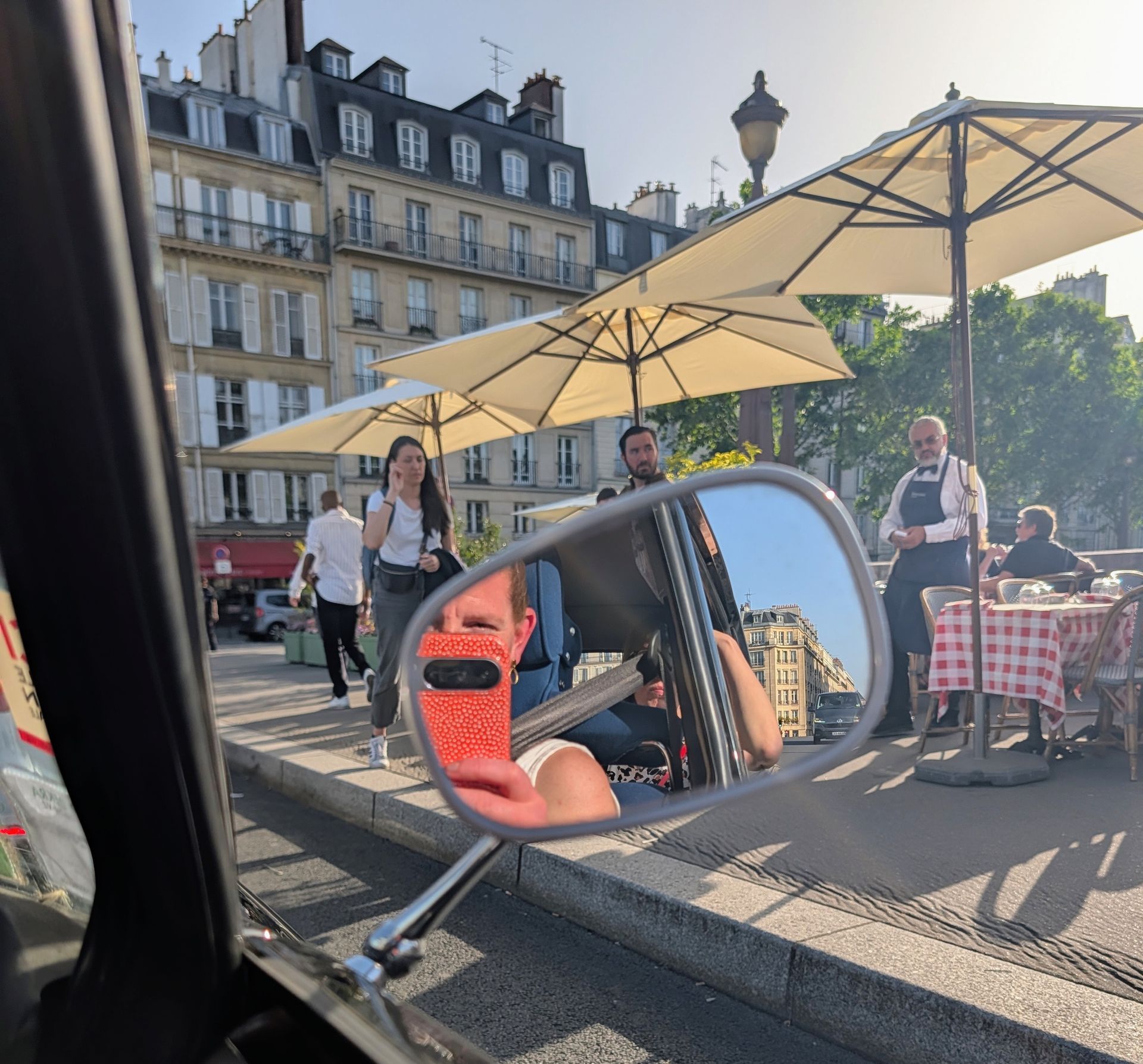Seitenspiegel und der Blick auf gedeckte Tische auf der Brücke Pont de la Tournelle in Paris.
