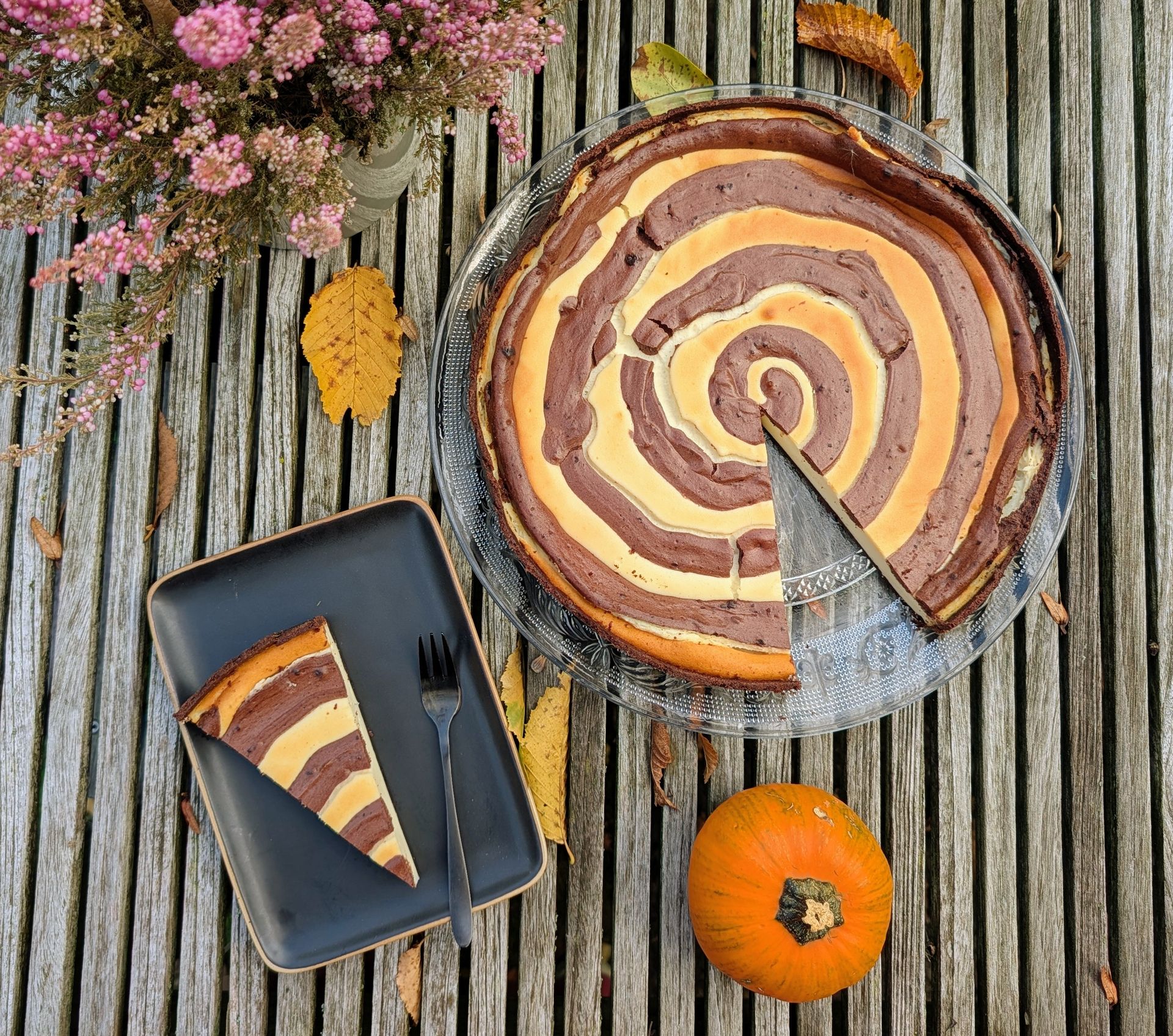 Pumpkin Spice Käsekuchen auf einem Holztisch mit Laub.