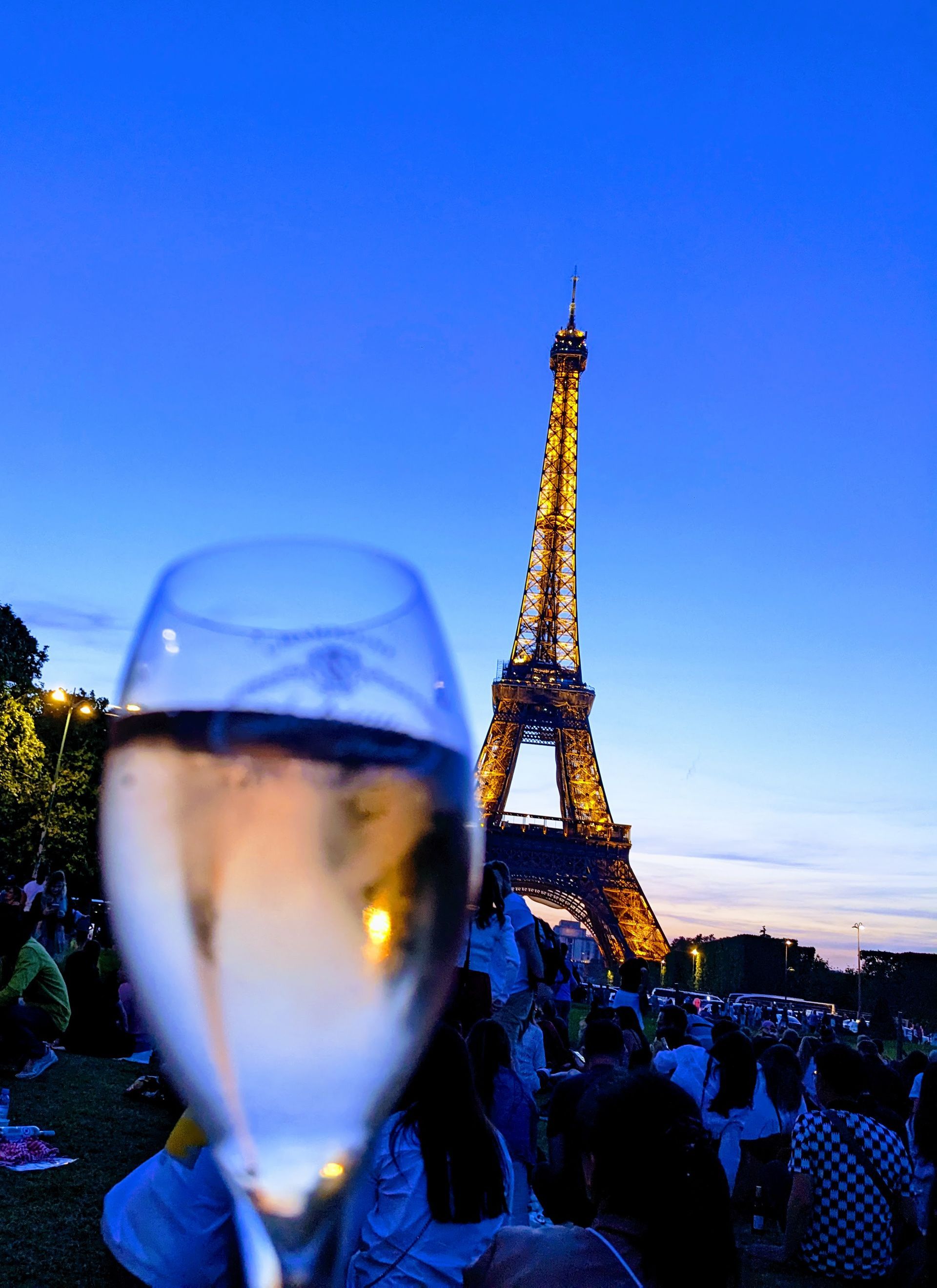 Ein Glas Rosé vor dem Eiffelturm bei Dämmerung.