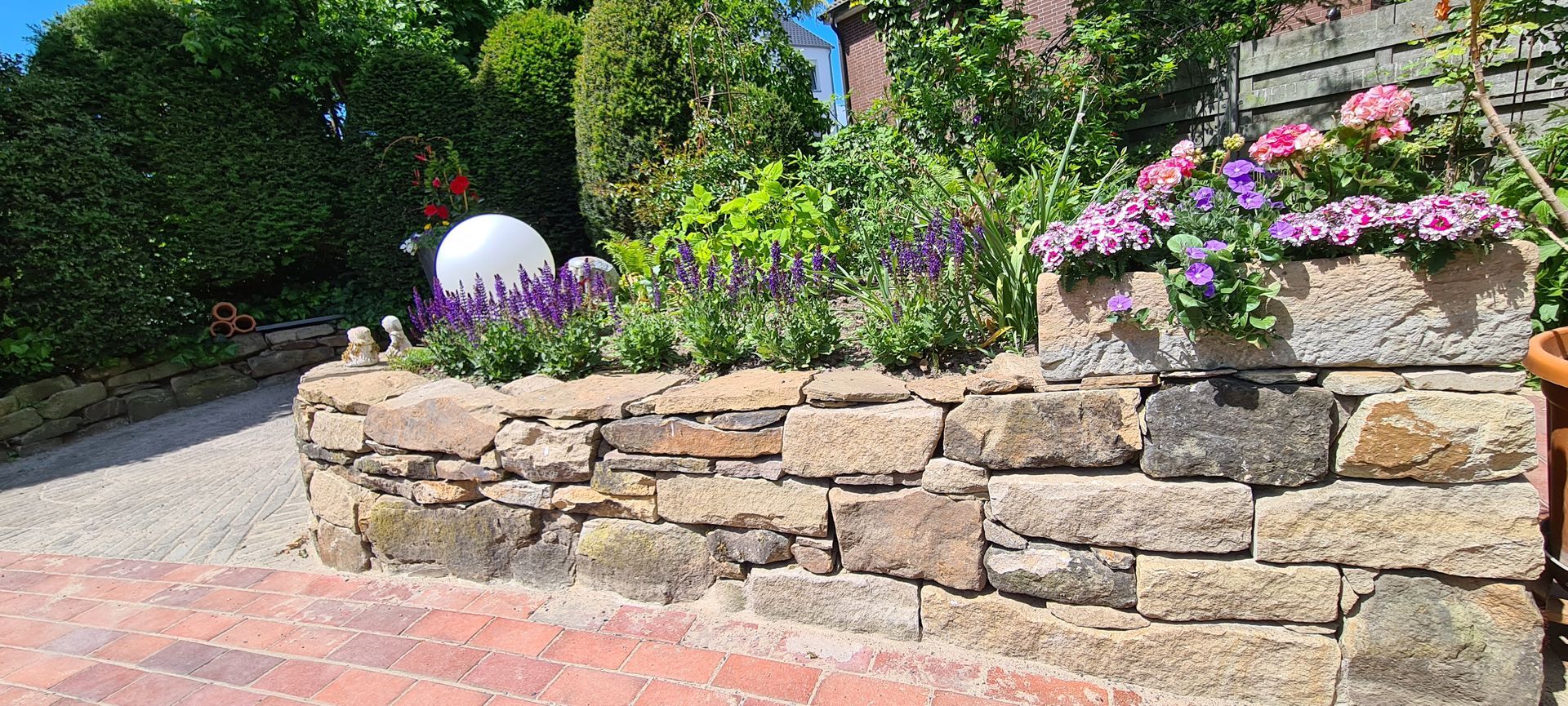 Eine Steinmauer mit Blumen, die in einem Garten wachsen