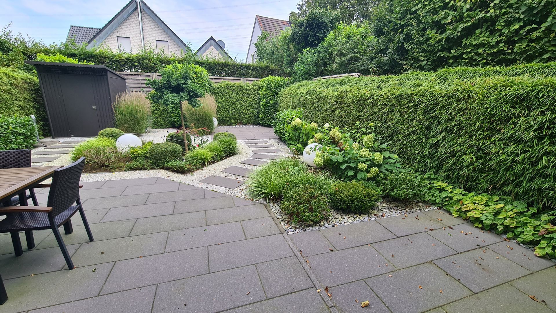 Eine Terrasse mit Tisch und Stühlen inmitten eines Gartens