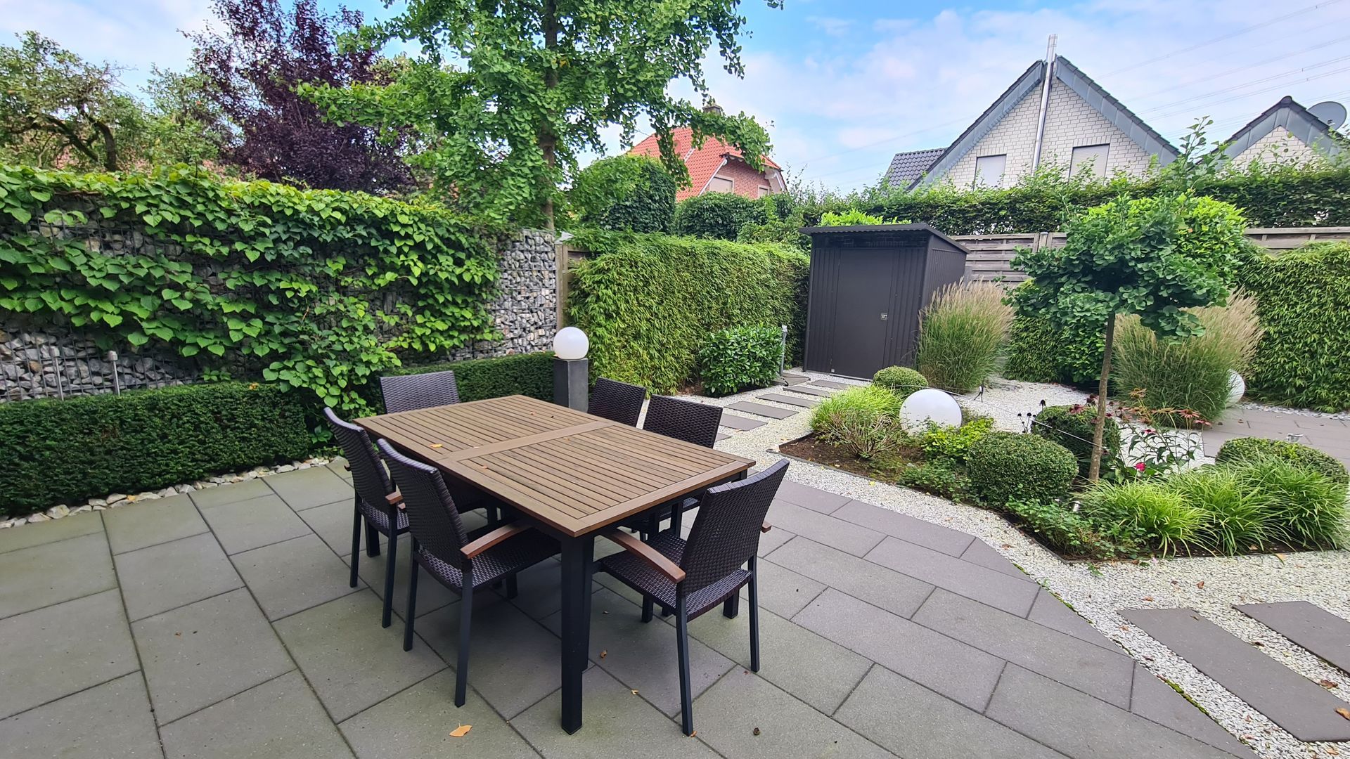 Ein Tisch und Stühle stehen auf einer Terrasse in einem Garten