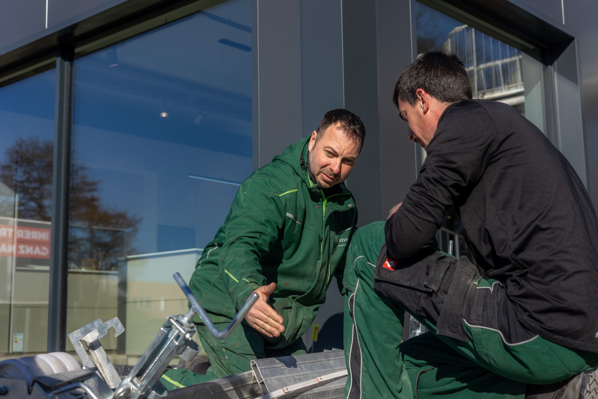Zwei Männer arbeiten an einem Rohr außerhalb eines Gebäudes