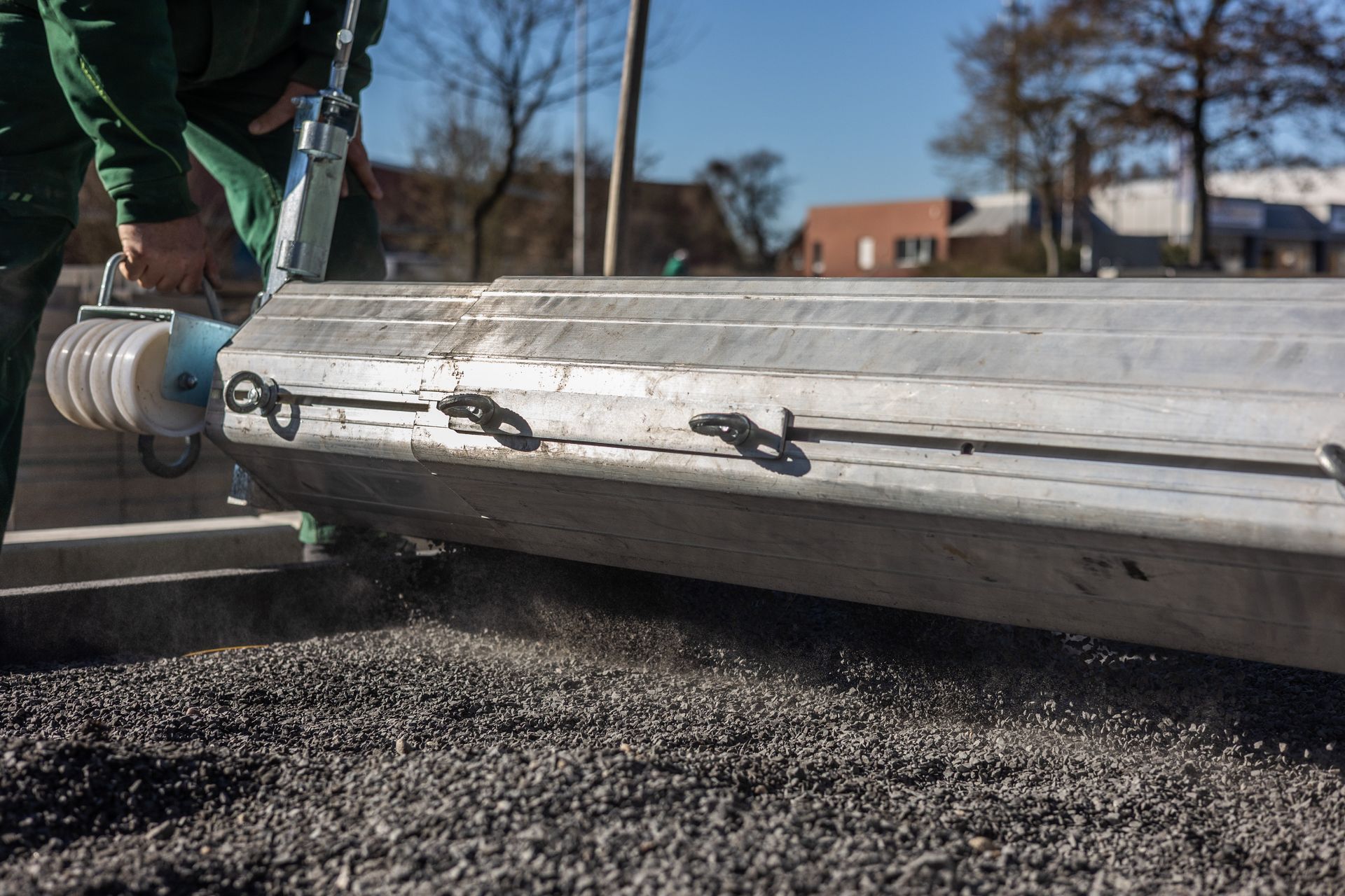 Ein Mann in einer grünen Jacke arbeitet an einem Stück Holz