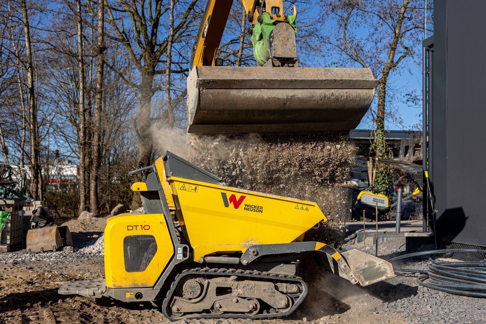 Ein gelber Muldenkipper wird von einer Planierraupe mit Erde beladen