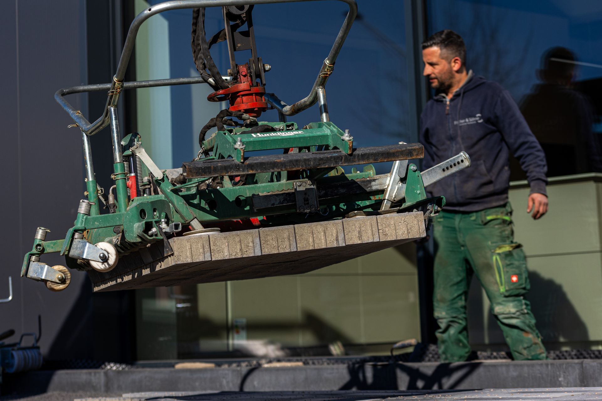 Ein Mann steht neben einer Maschine, die ein Stück Beton anhebt