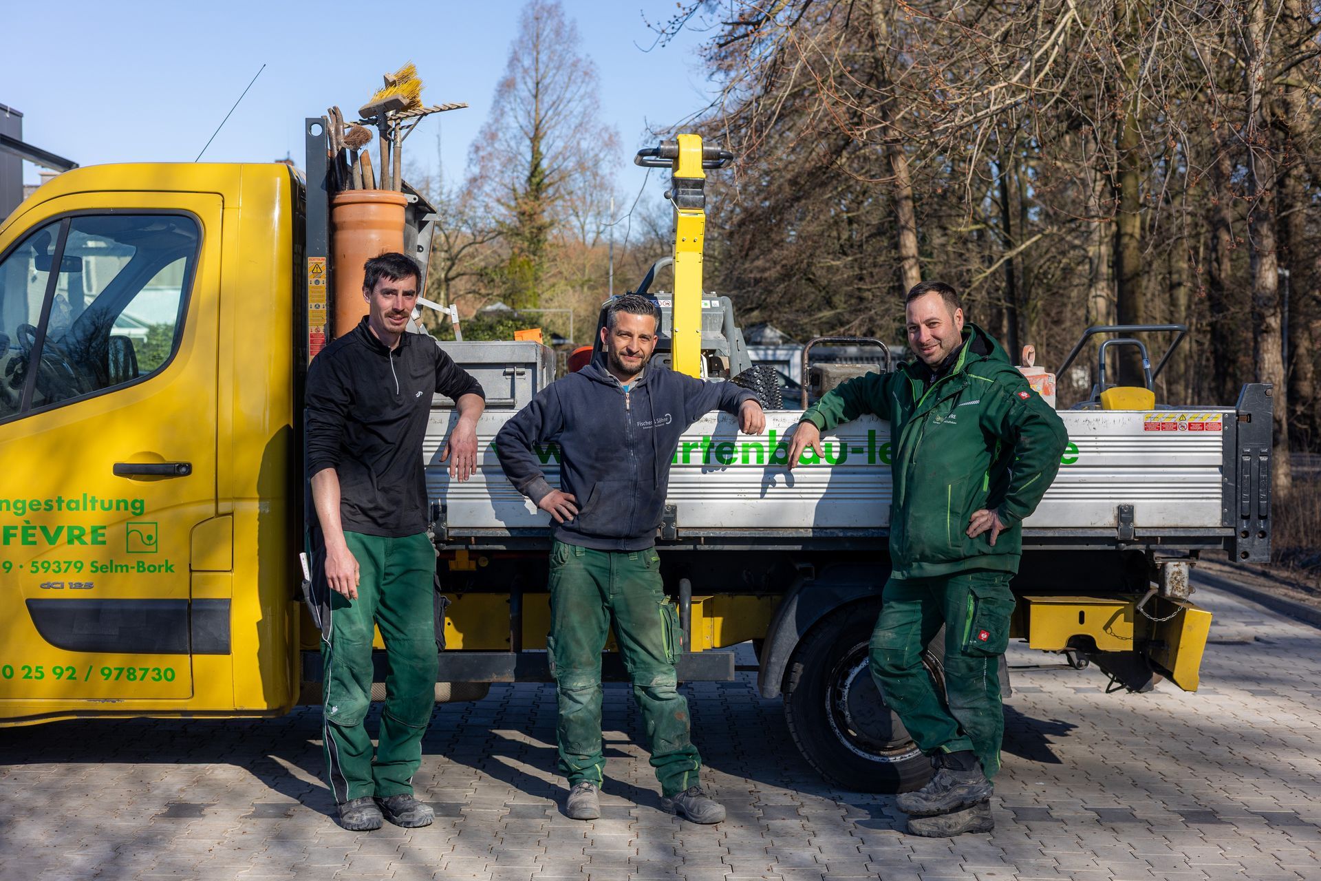 Drei Männer stehen vor einem gelben Lastwagen
