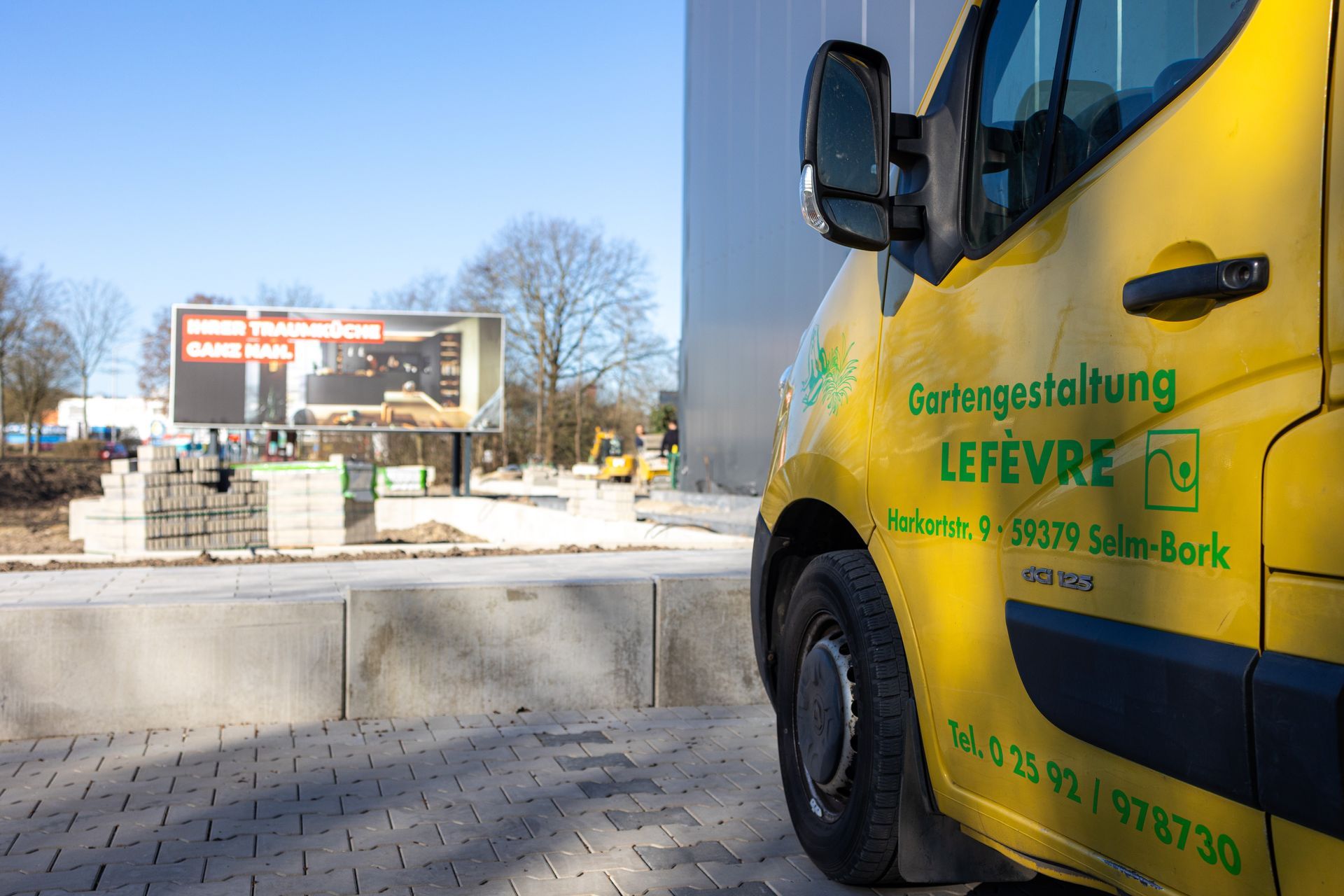 Ein gelber Lefevre Lieferwagen parkt vor einem im Bau befindlichen Gebäude