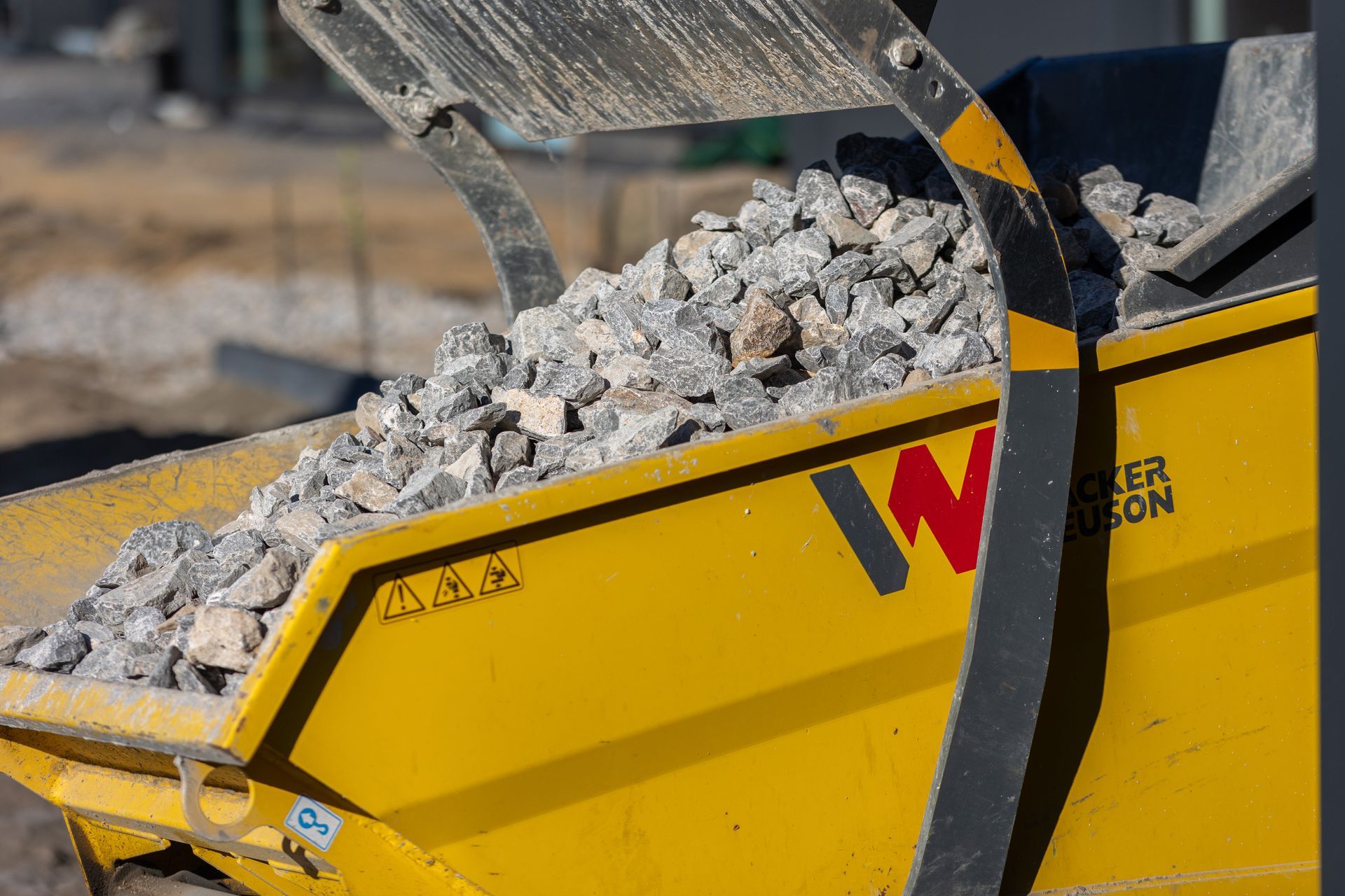 Ein gelber Müllcontainer voller Steine ​​auf einer Baustelle