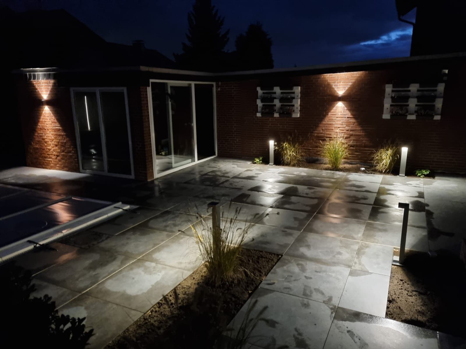 Ein Backsteingebäude ist nachts beleuchtet und hat eine Terrasse davor
