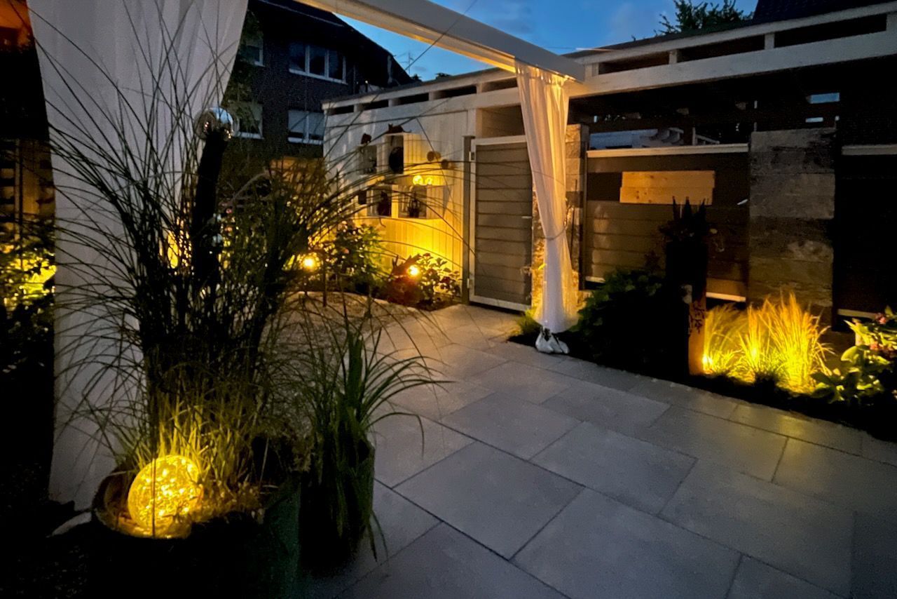 Eine Terrasse mit Pergola und nachts beleuchteten Pflanzen