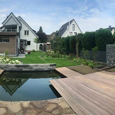 Ein Haus mit einem Teich davor und einer Holzterrasse