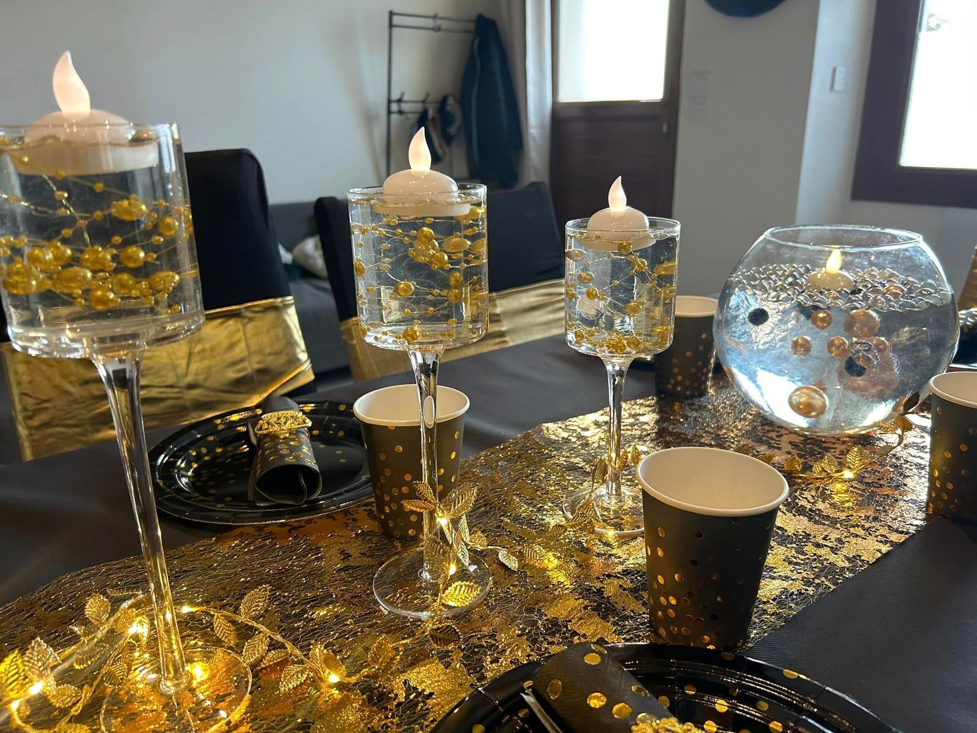 Bougies dans des verres à pieds pour une soirée noire et dorée