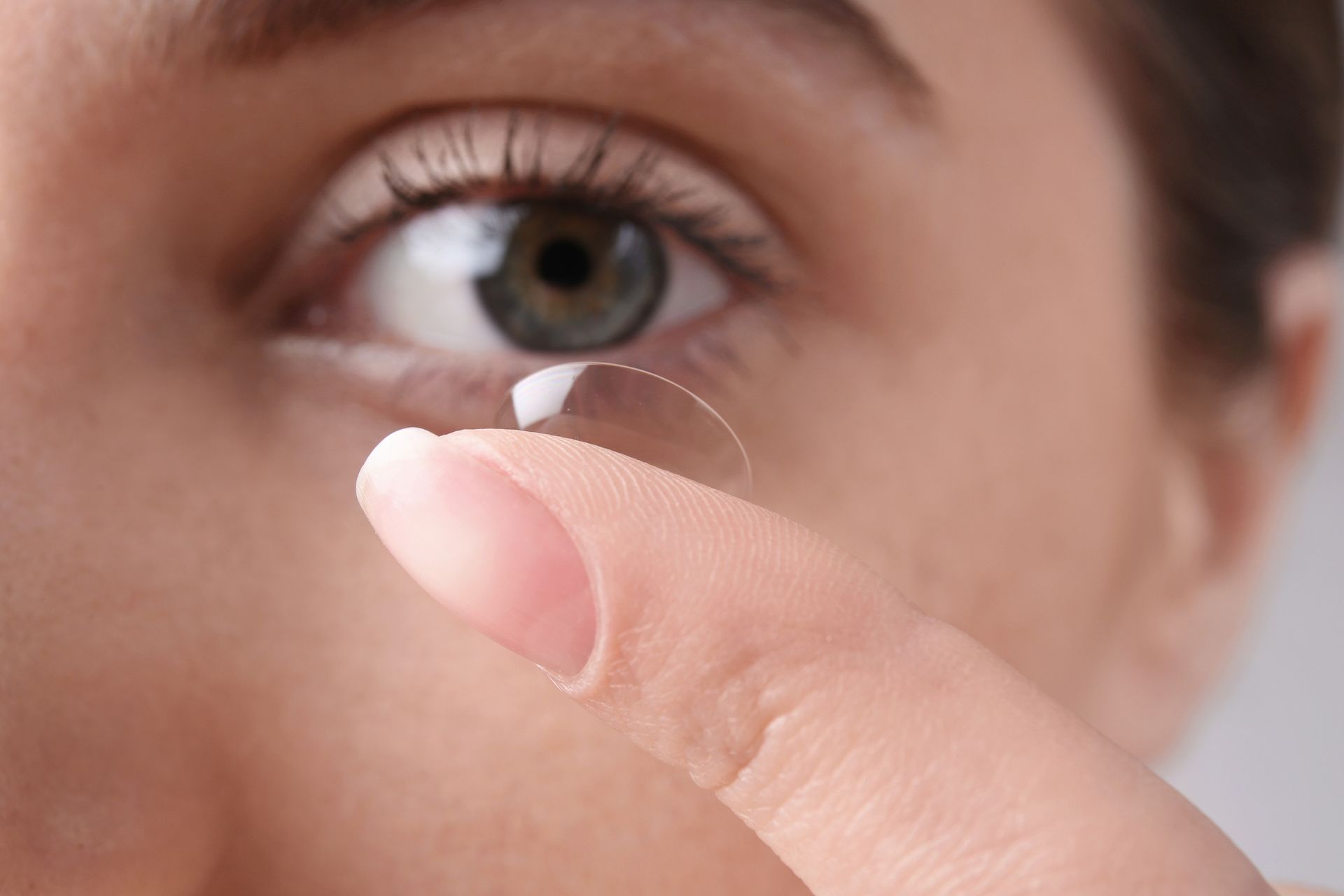 Una mujer se pone una lente de contacto en el ojo.