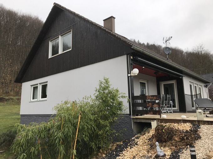 Maison à deux étages avec extérieur supérieur brun foncé et extérieur inférieur blanc.