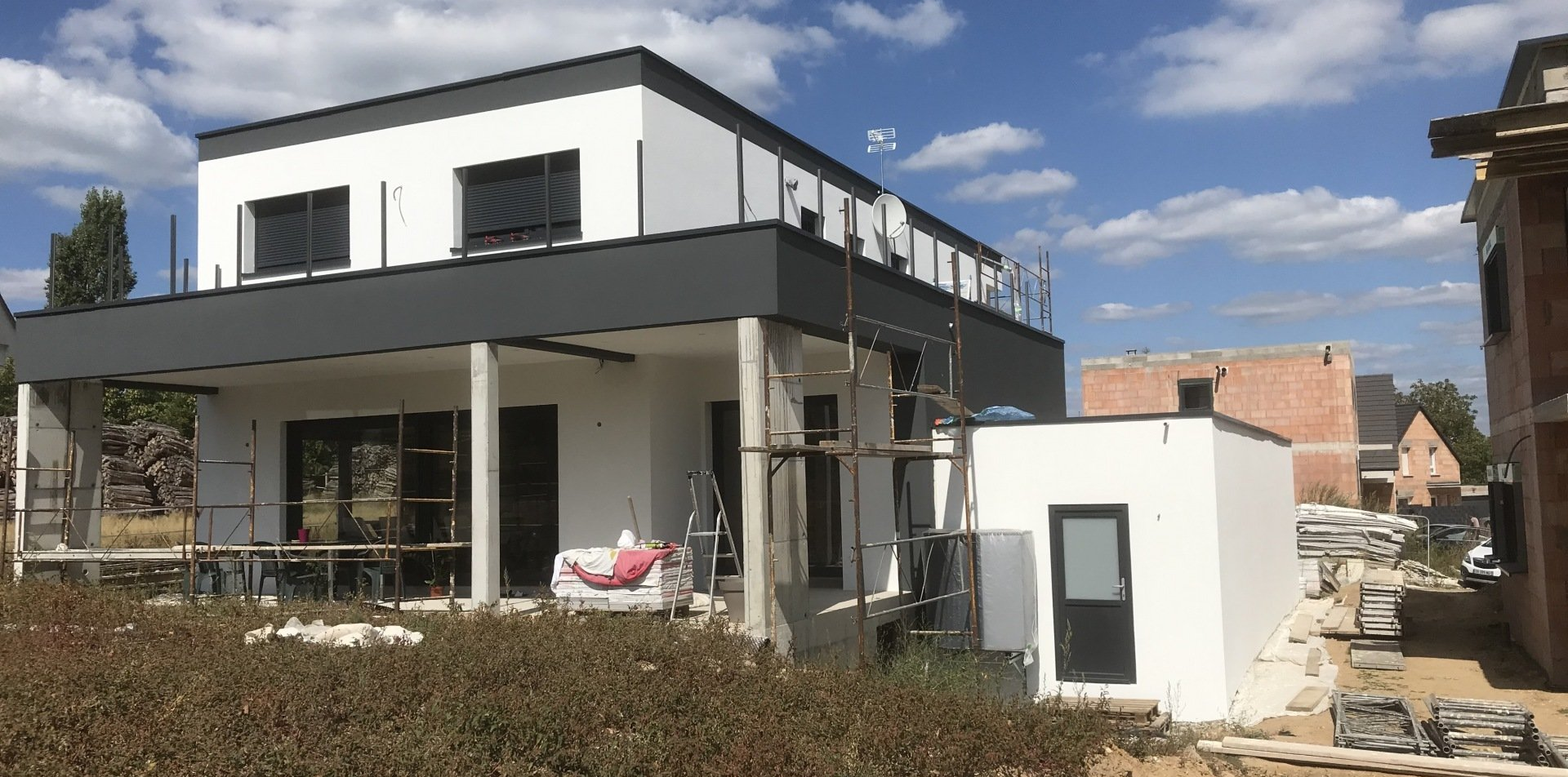 Maison moderne à deux étages en construction avec murs blancs.
