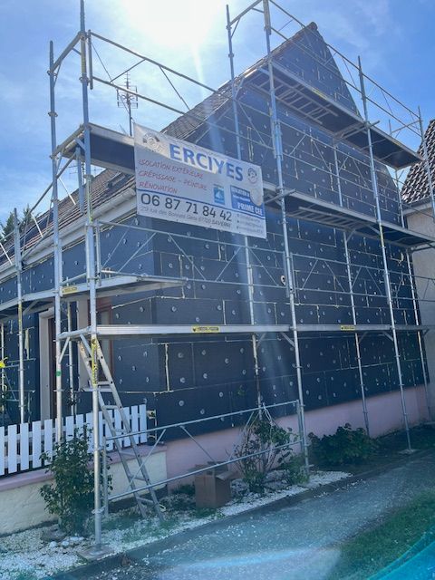 Extérieur de maison en rénovation, échafaudage et isolation noire.