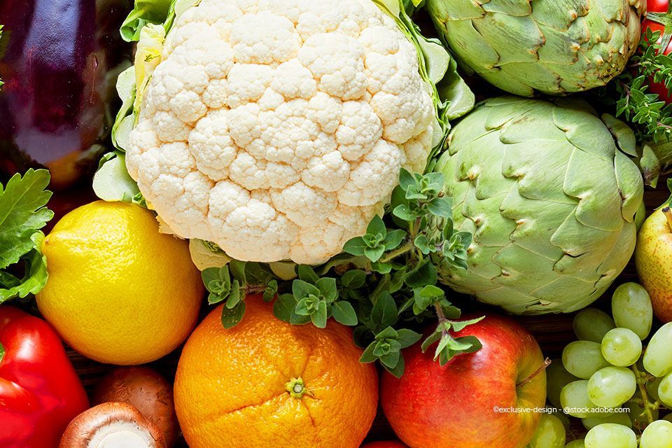 Nahaufnahme verschiedener bunter Obst- und Gemüsesorten, darunter Blumenkohl, Zitrone, Orange und Apfel.