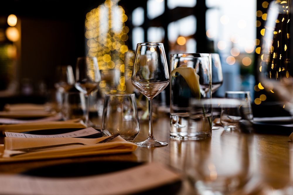 Una mesa con platos, tenedores, cuchillos y copas de vino sobre ella.