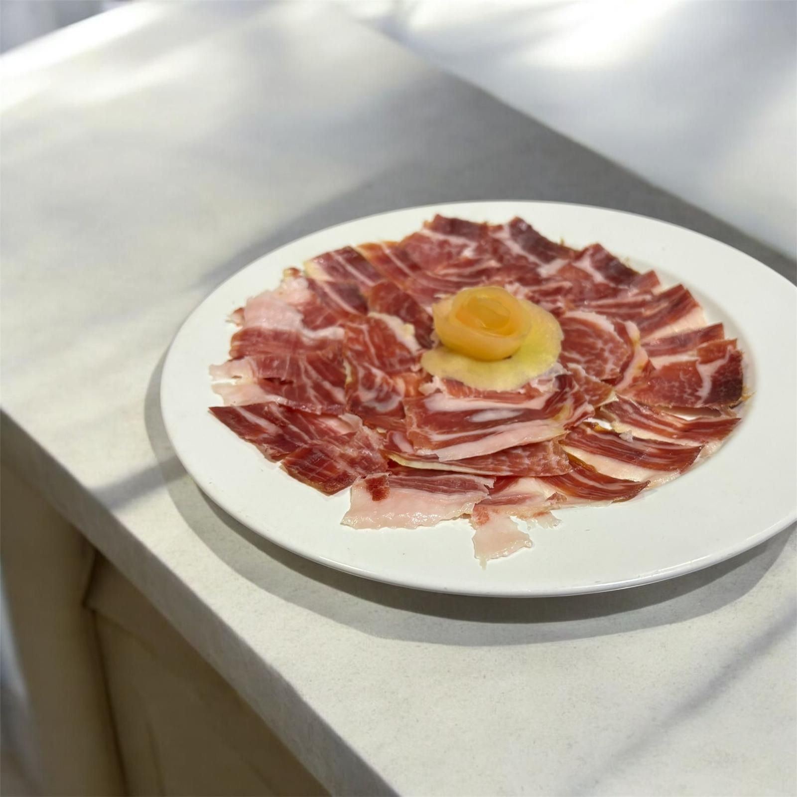 Un plato blanco cubierto con jamón y una salsa.