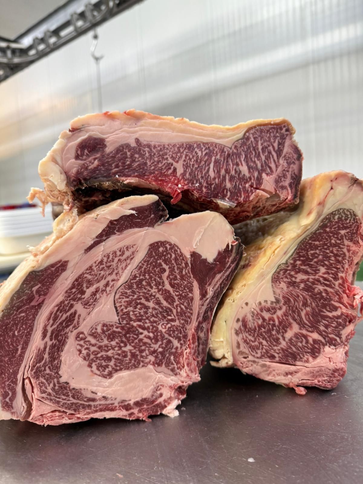 Tres trozos de carne cruda están apilados uno encima del otro sobre una mesa.