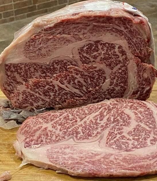 Un gran trozo de carne reposa sobre una tabla de cortar de madera.