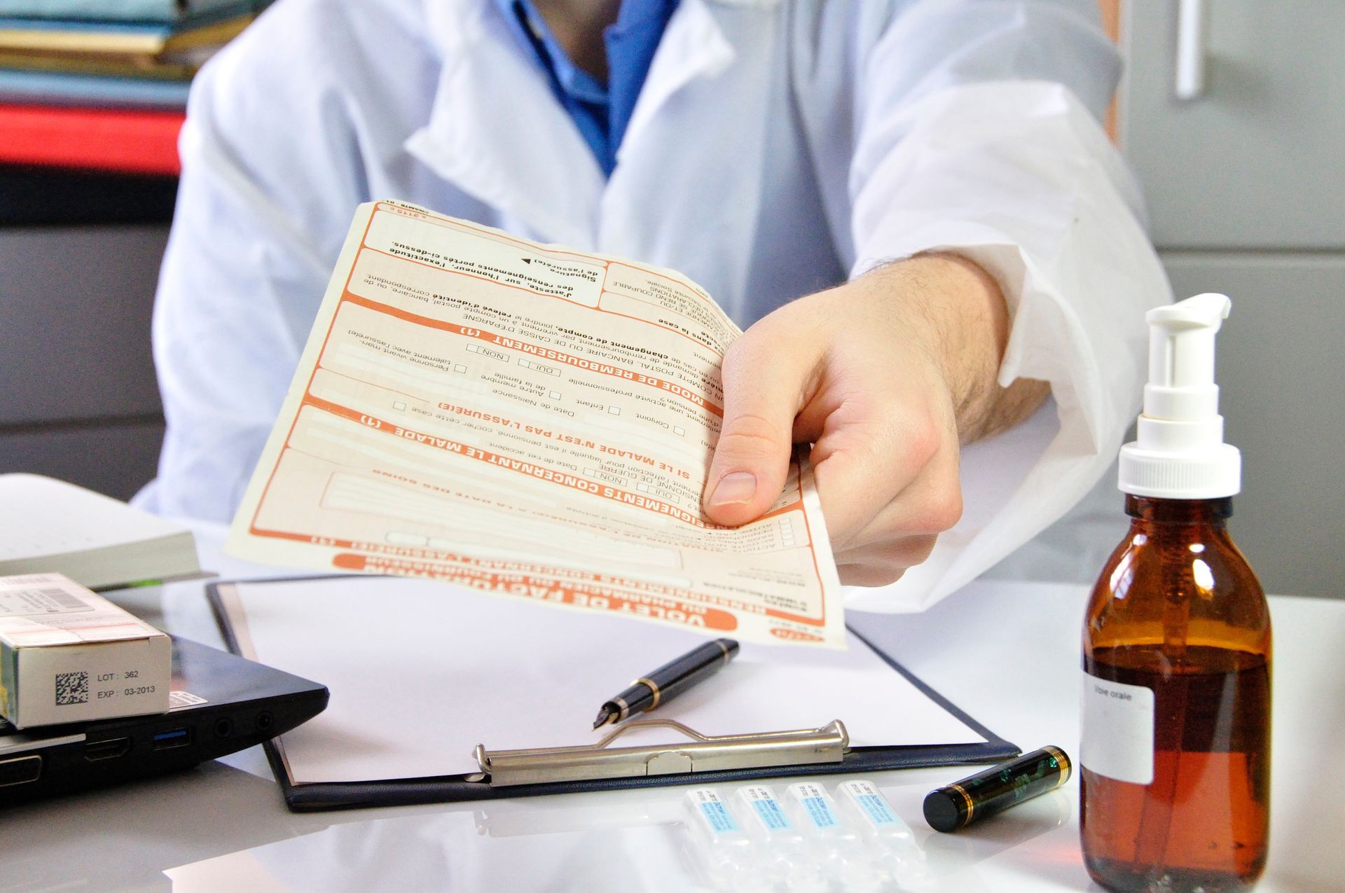 Un pharmacien tend une ordonnance à côté de flacons de médicament et d'un bloc-notes.