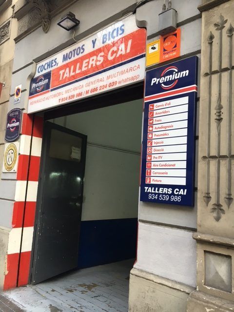 Exterior del taller de reparación de motos y bicicletas TALLERS CAI con puerta abierta y lista de servicios.