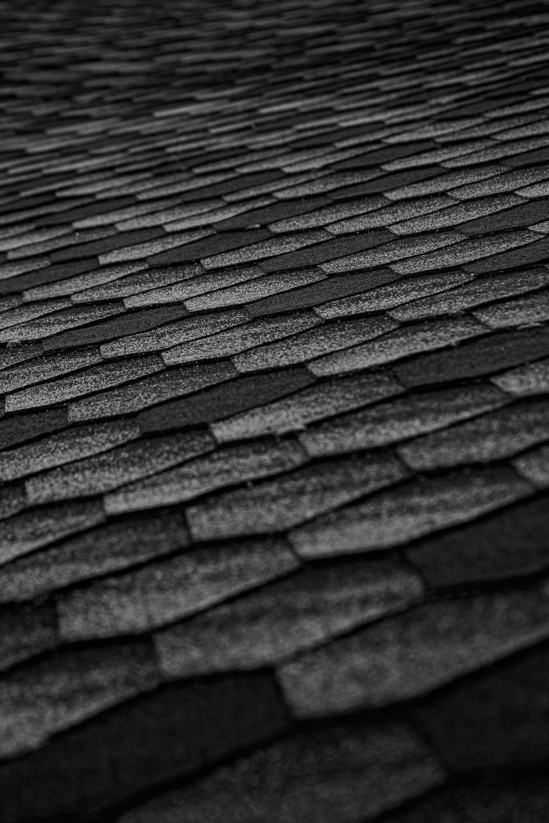 Close-up of overlapping dark gray roof shingles with a textured pattern