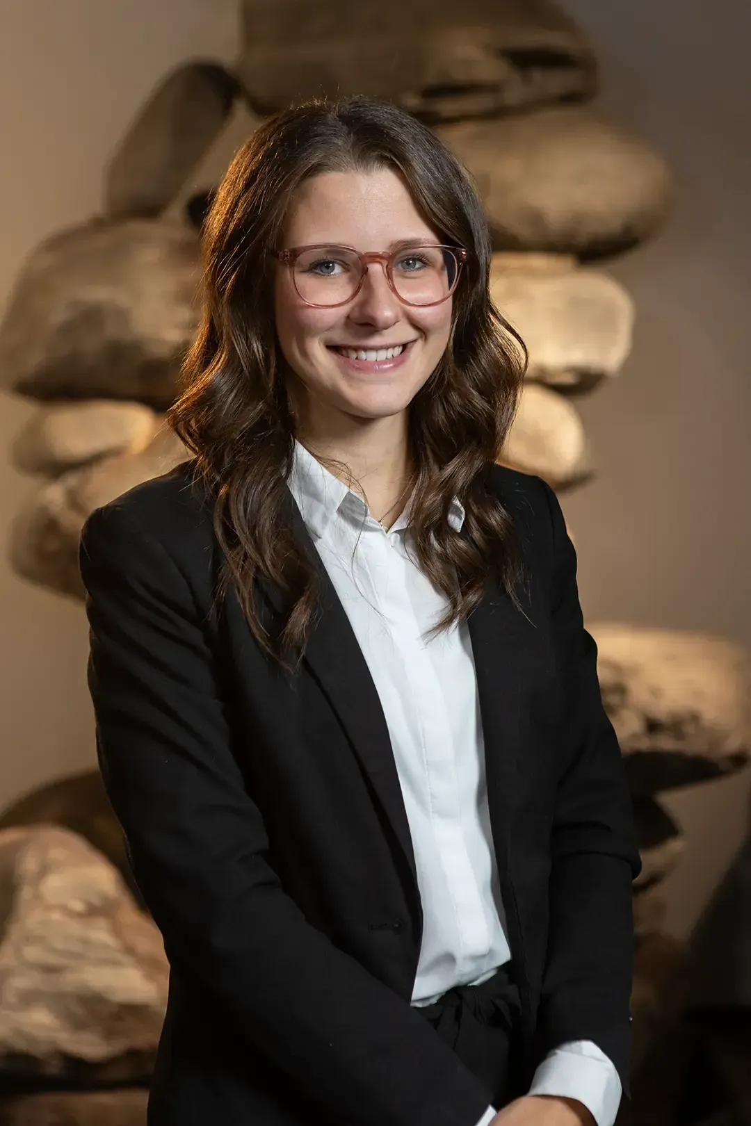 Eine Frau mit Brille und weißem Hemd lächelt in die Kamera.