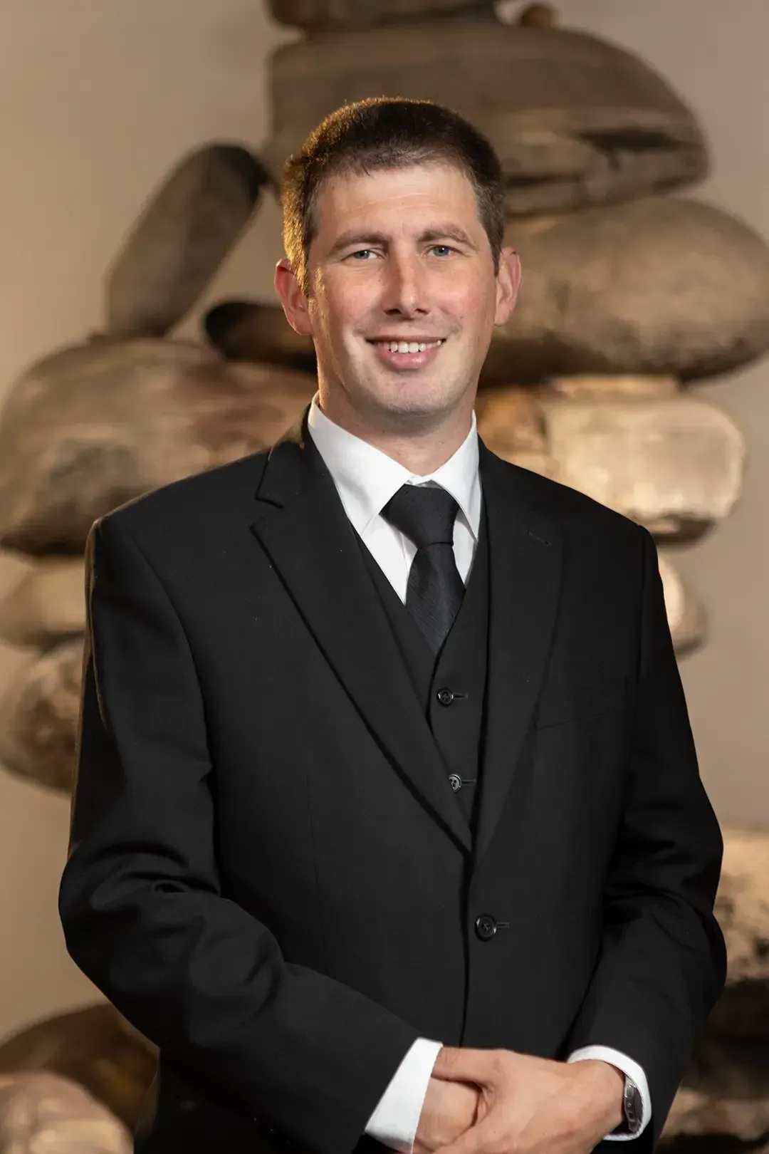 Ein Mann in Anzug und roter Krawatte lächelt in die Kamera