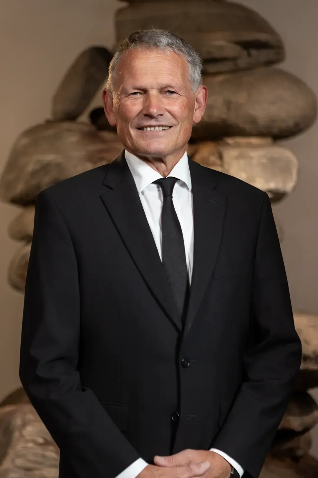 Ein Mann in Anzug und roter Krawatte lächelt in die Kamera