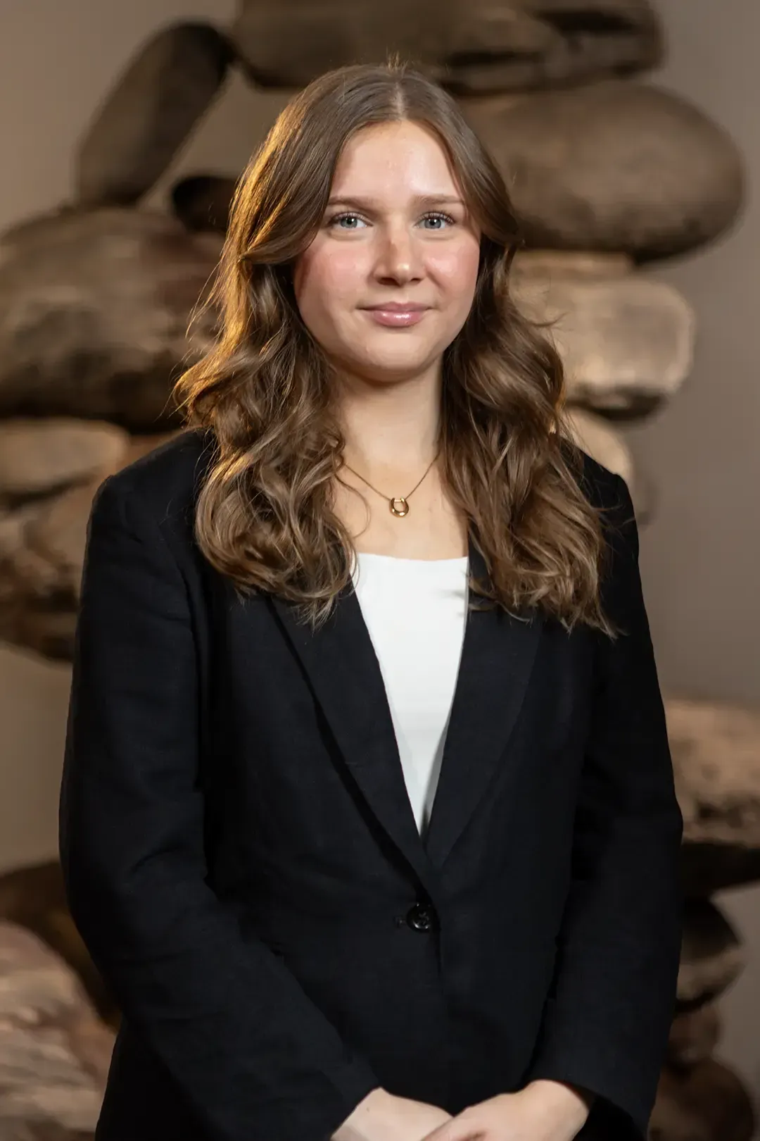 Eine junge Frau mit einem schwarzen Rollkragenpullover und Ohrringen blickt in die Kamera.