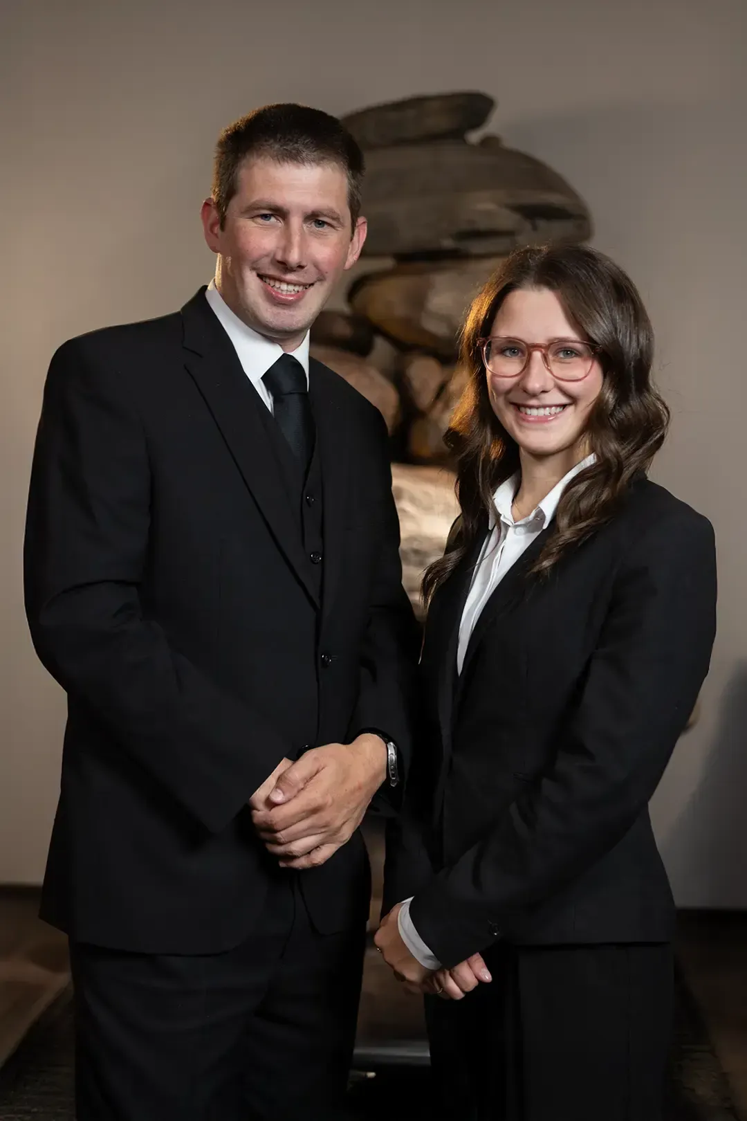 Ein Mann in Anzug und roter Krawatte lächelt in die Kamera